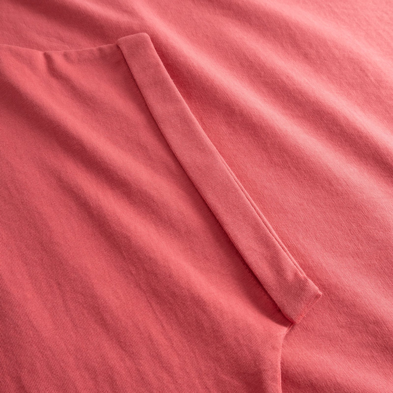 A close-up of the soft, Holly Red organic cotton fabric on the T-shirt Visby Base, showing the neat folded sleeve detail.