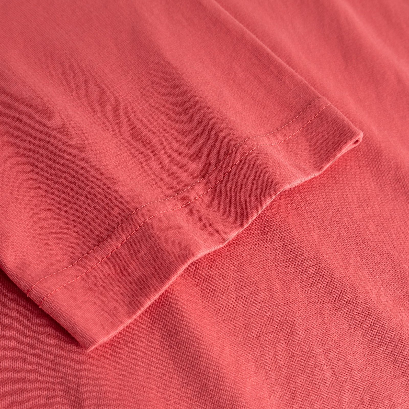 A detailed close-up of the sleeve on the T-shirt Vadstena in Holly Red, crafted from soft organic cotton.