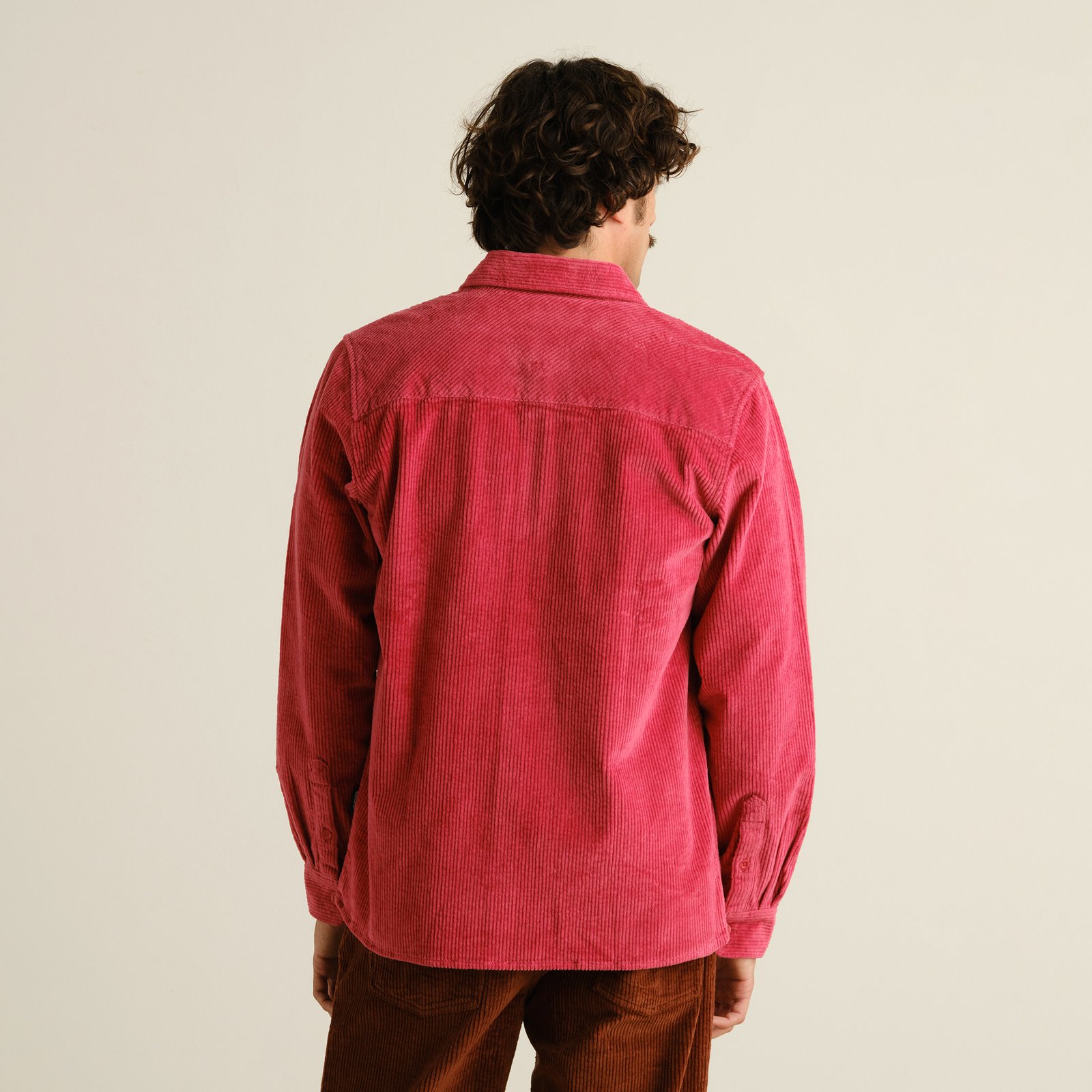 Rear view of a model wearing the Shirt Kil Corduroy in Holly Red, showcasing the overshirt's relaxed fit and texture.