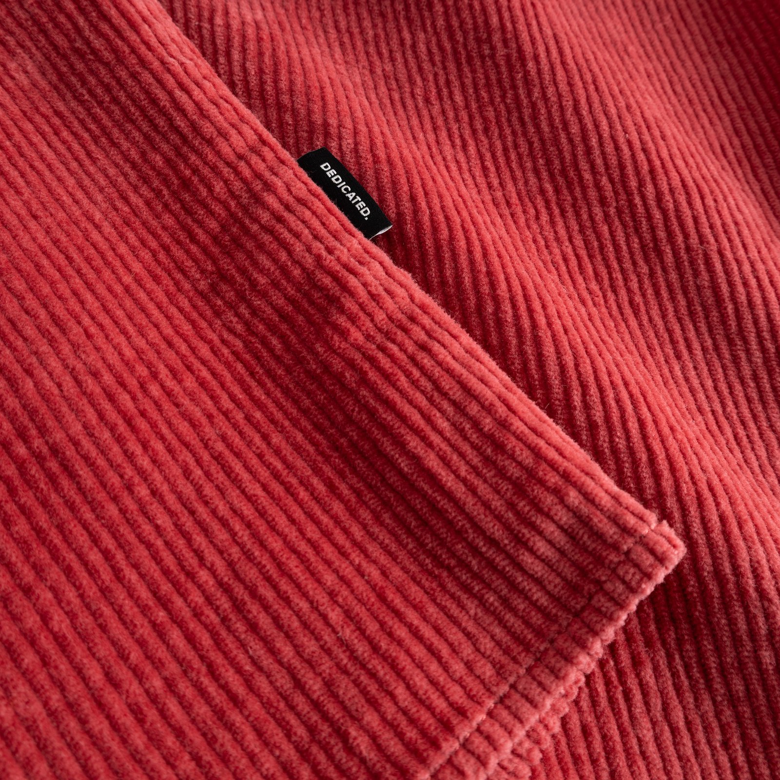 A detailed shot of the Shirt Kil Corduroy in Holly Red, focusing on its soft, ribbed texture and the Dedicated brand label.