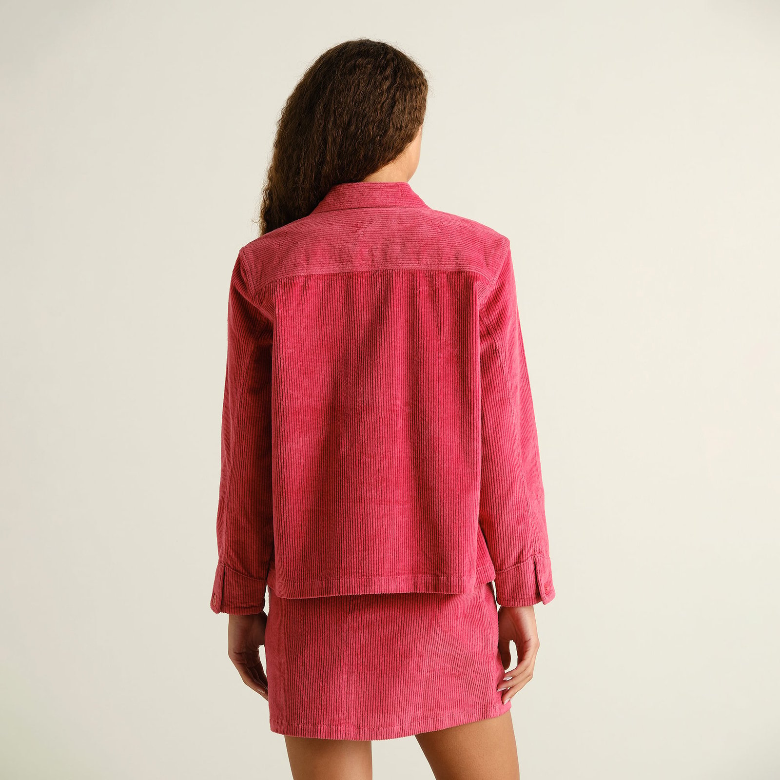 The Stiby Corduroy Jacket in Holly Red, seen from the back on a model wearing the matching skirt for a fun, coordinated look.