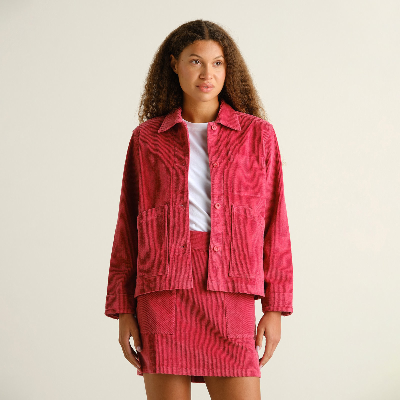 A model styles the Holly Red Stiby Corduroy Jacket with its matching skirt for a vibrant, coordinated look in our studio.