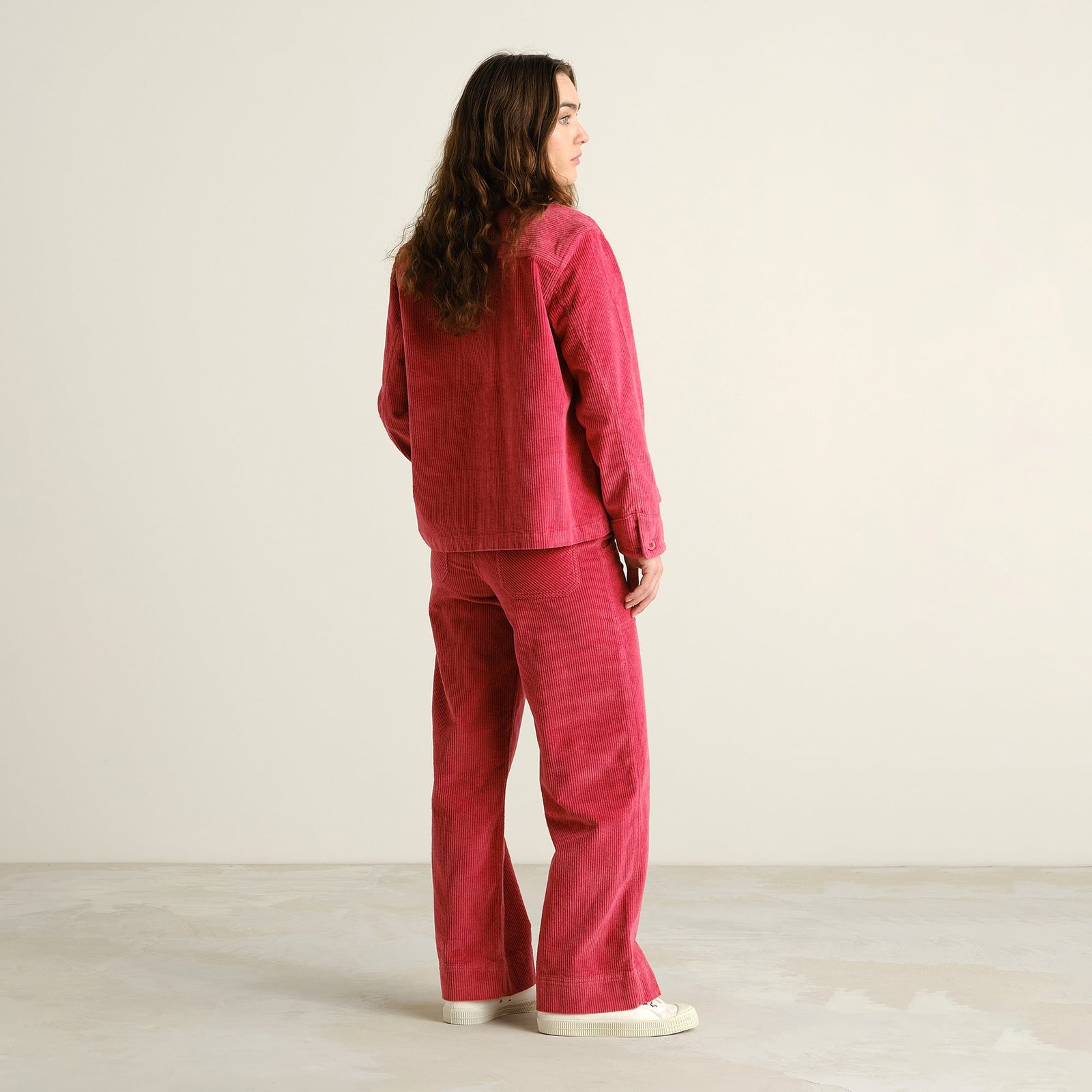 Model from behind shows the flattering wide-leg fit of the Vara Corduroy pants in Holly Red, styled with a matching jacket.
