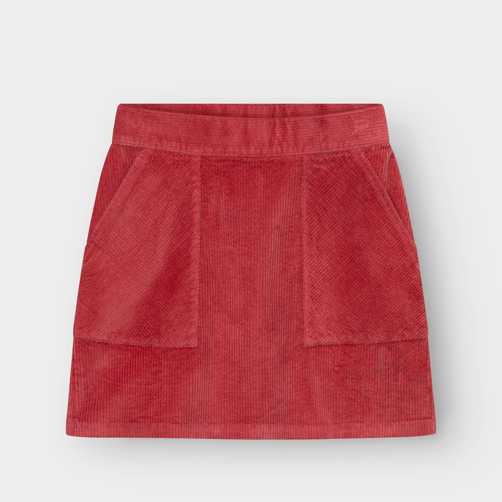 Studio shot of the Skirt Majorna Corduroy in Holly Red, a short A-line skirt with two large front patch pockets.