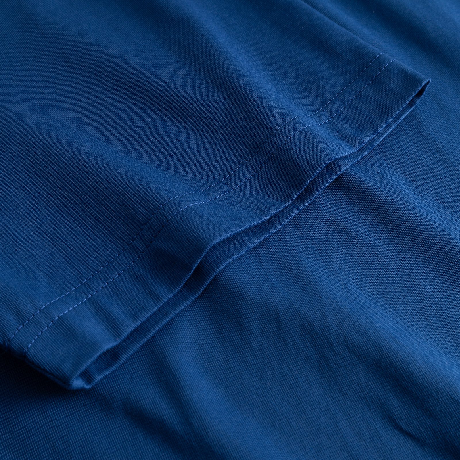 Närbild på ärmen på T-shirten Stockholm Base i Limoges Blue, som visar tyget och de detaljerade sömmarna.