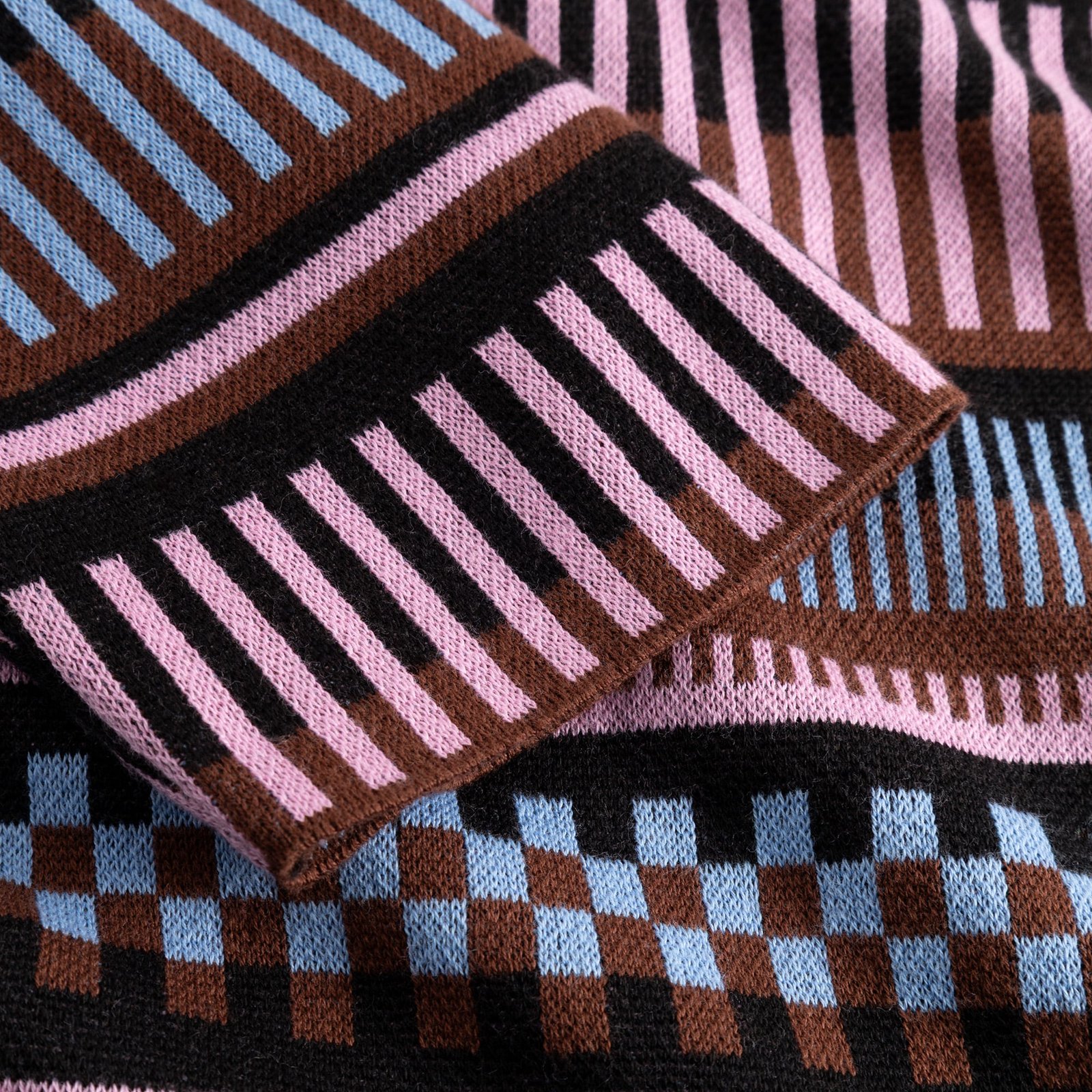 Close-up of the Sweater Limhamn's sleeve, showcasing the intricate jacquard knit with a colorful dashed stripe pattern.