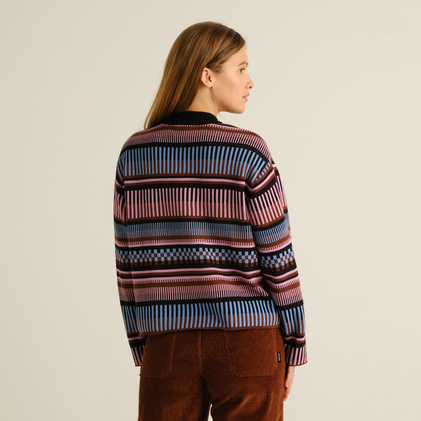 Model from behind wearing the multi-colored Sweater Limhamn Dashed Stripe paired with brown corduroy trousers.