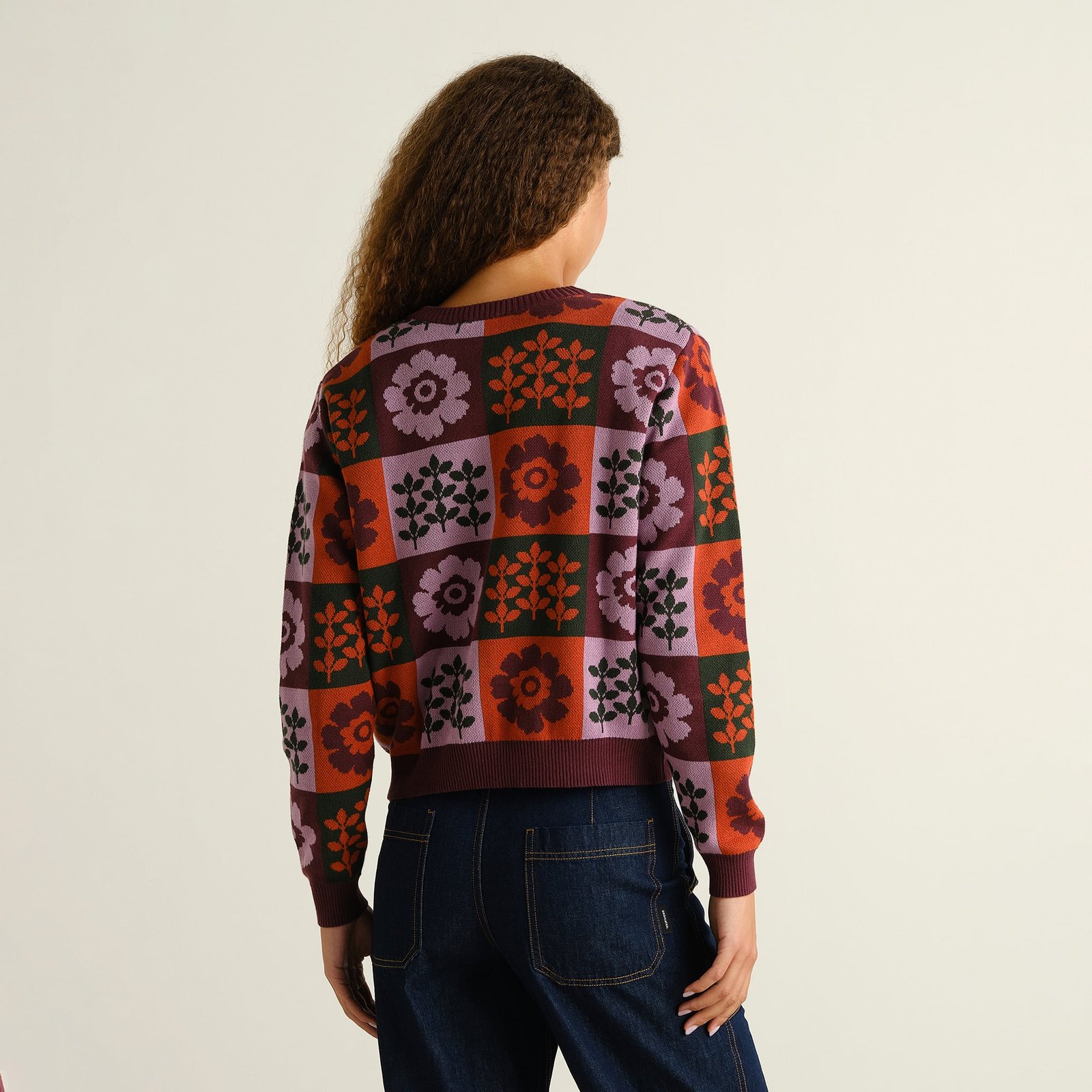 Model with her back to the camera wearing the colorful floral patterned Sweater Arendal Nature Check Multi Color with jeans.