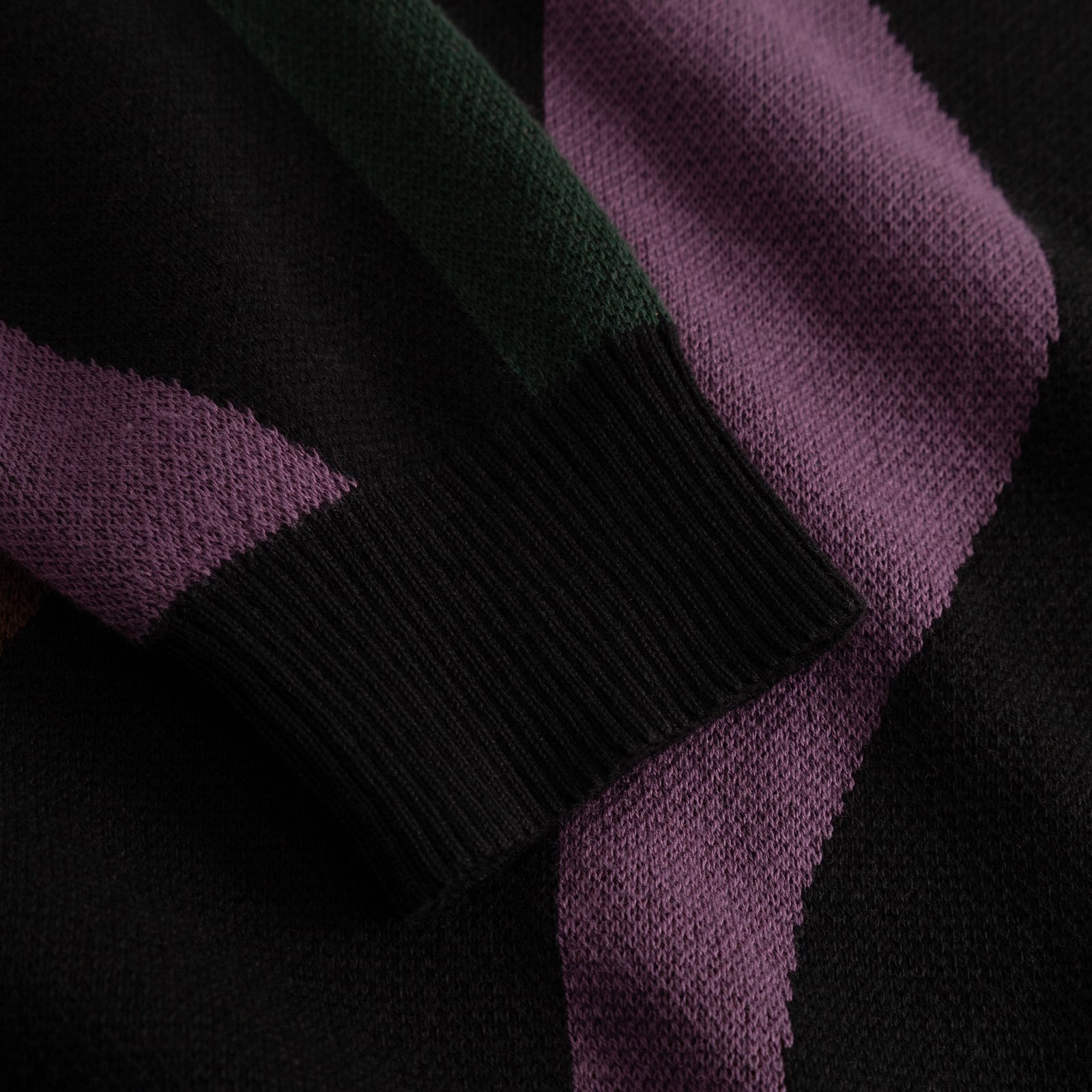 A close-up detail shot of the Arendal sweater's ribbed cuff, showing the texture of the wavy multi-color jacquard knit.
