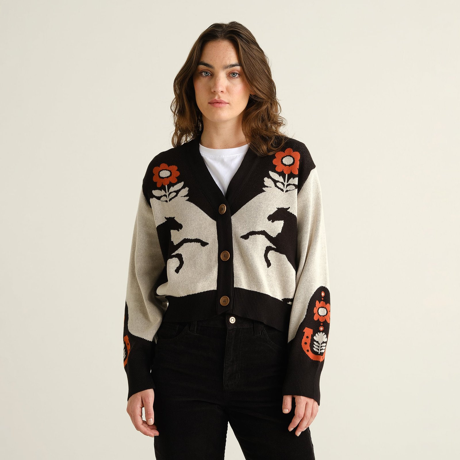 Model wears the Cardigan Kanan Western Multi Color, a knitted V-neck with a unique jacquard pattern of horses and flowers.