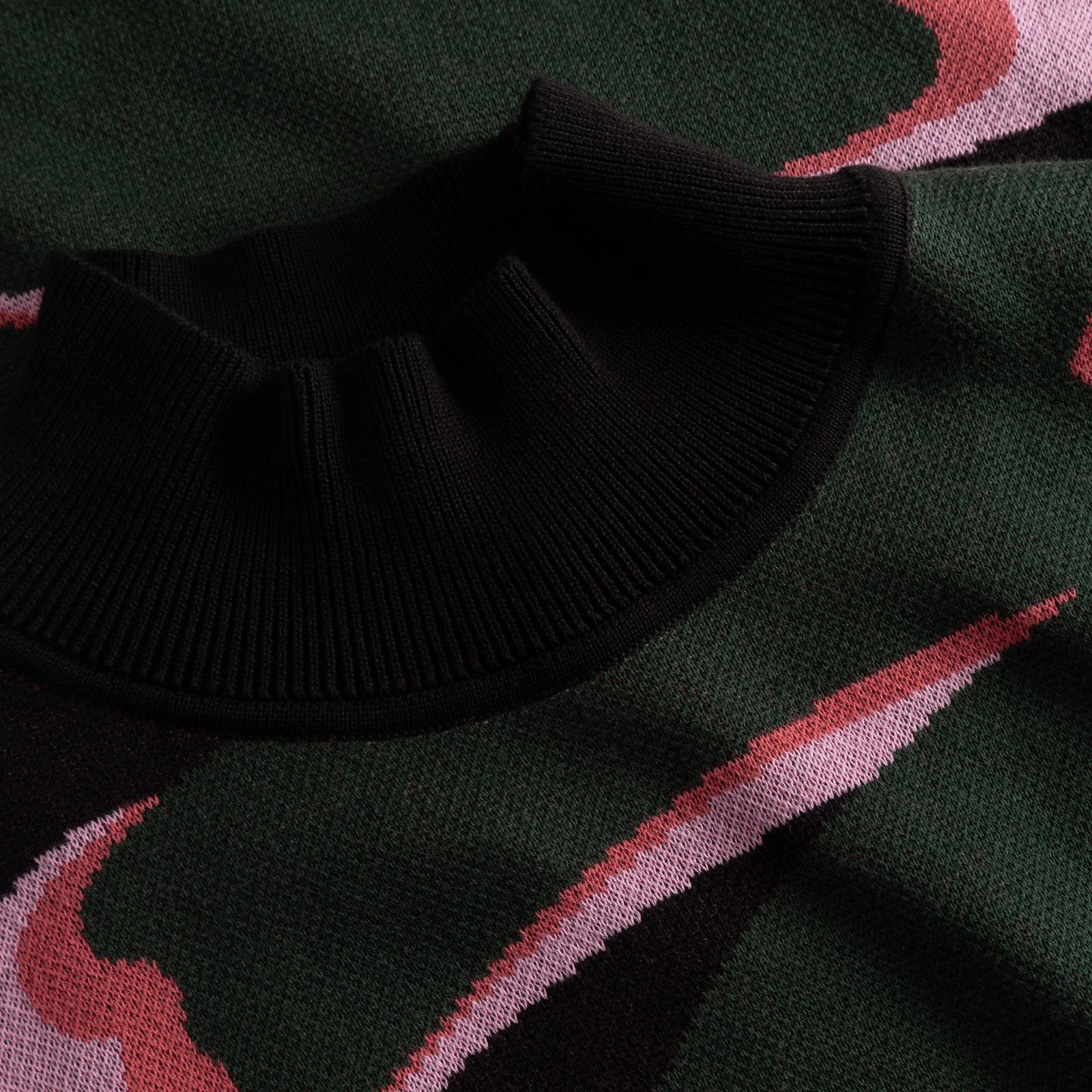 Nahaufnahme des schwarzen Rippkragens des Kleides Nikkala Big Bloom mit Jacquard-Strickmuster in Grün und Pink.