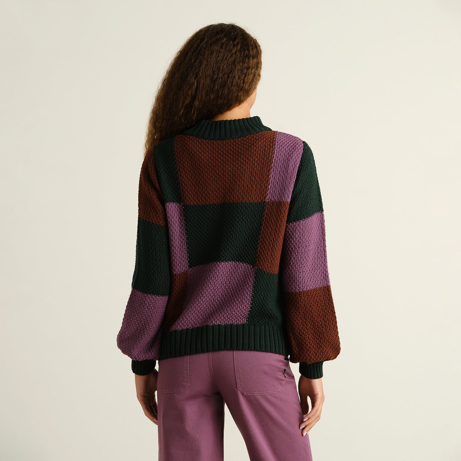 A woman seen from behind, showing off the relaxed fit of the chunky Gotland sweater in a bold multi-color block pattern.