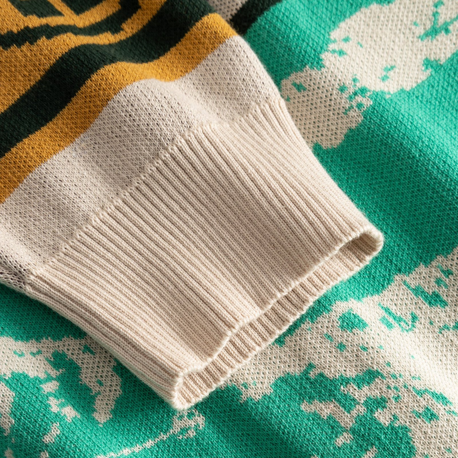 Närbild på den ribbstickade mudden och den färgglada, jacquardstickade ärmen på Cardigan Delsbo Retro Ski Blocks.