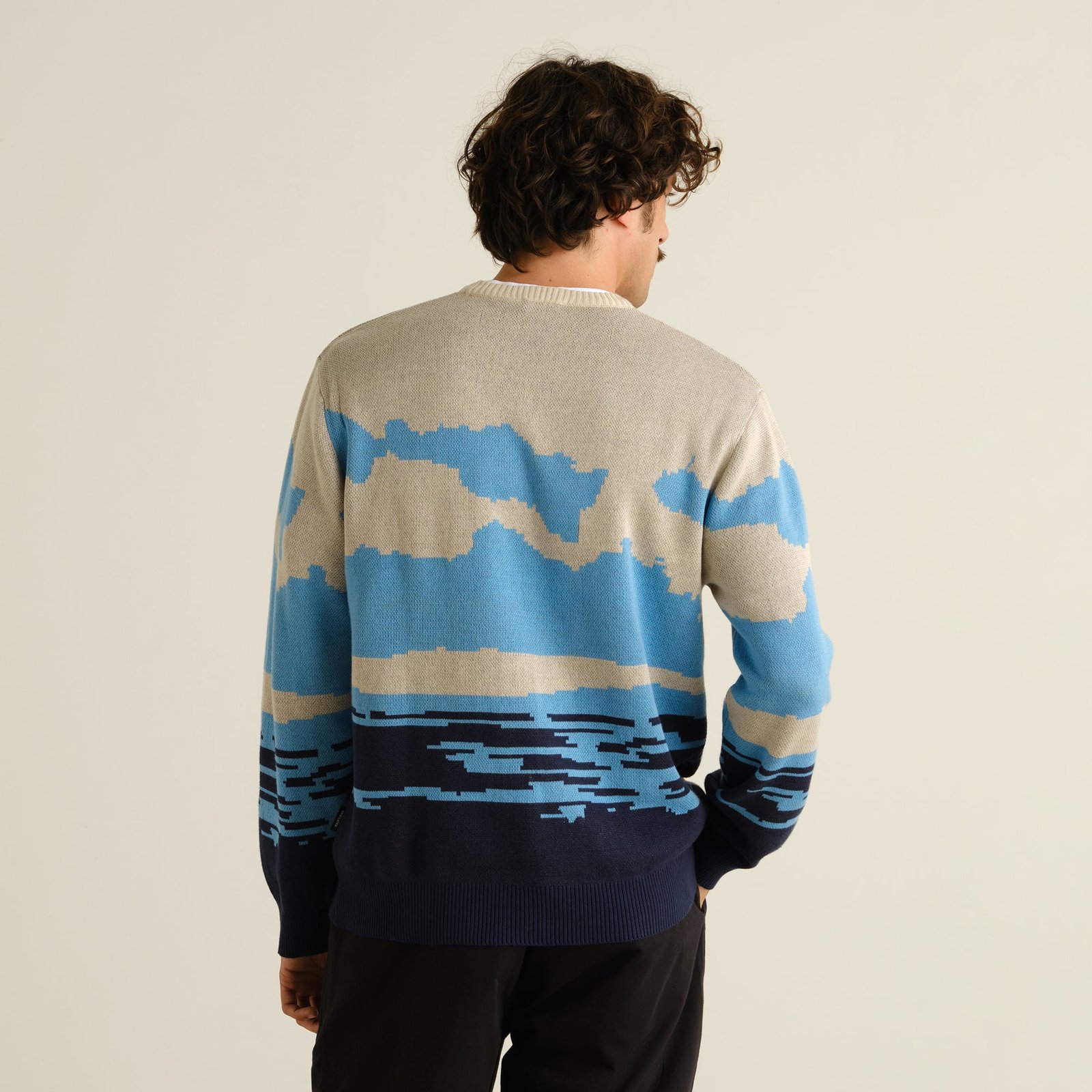 Back view of a model wearing the Sweater Mora, showcasing the cool 'Man and Sea' jacquard knit design in multiple colors.