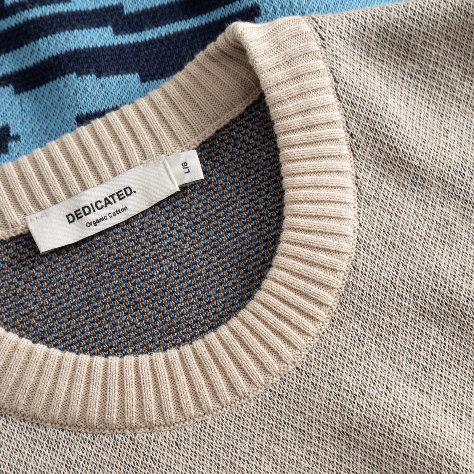 Detail shot of the Sweater Mora Man and Sea, showing the texture of the jacquard knit and the ribbed neckline with brand tag.