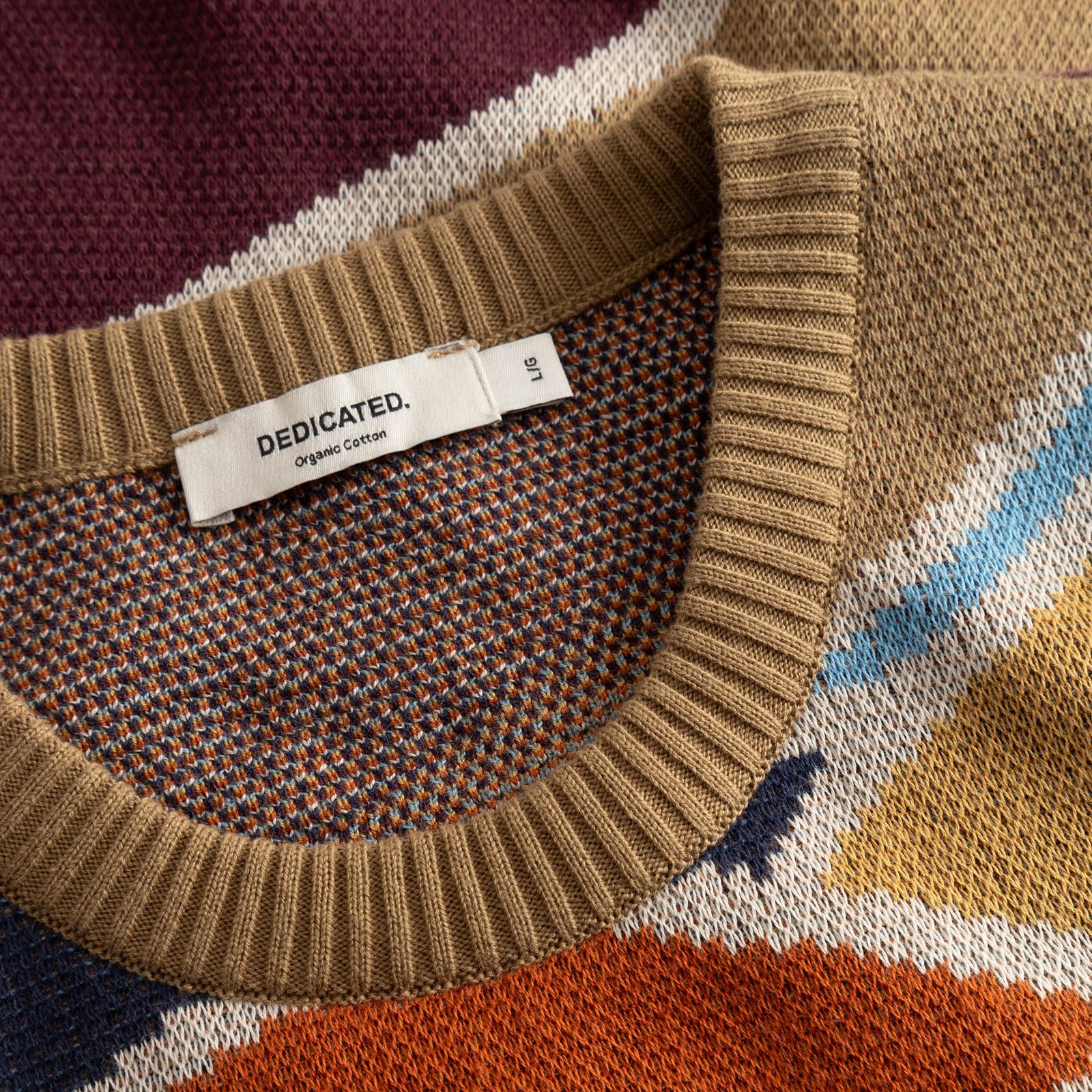 Detailed shot of the Sweater Mora's ribbed neckline, showcasing its intricate multi-colored jacquard knit and brand tag.