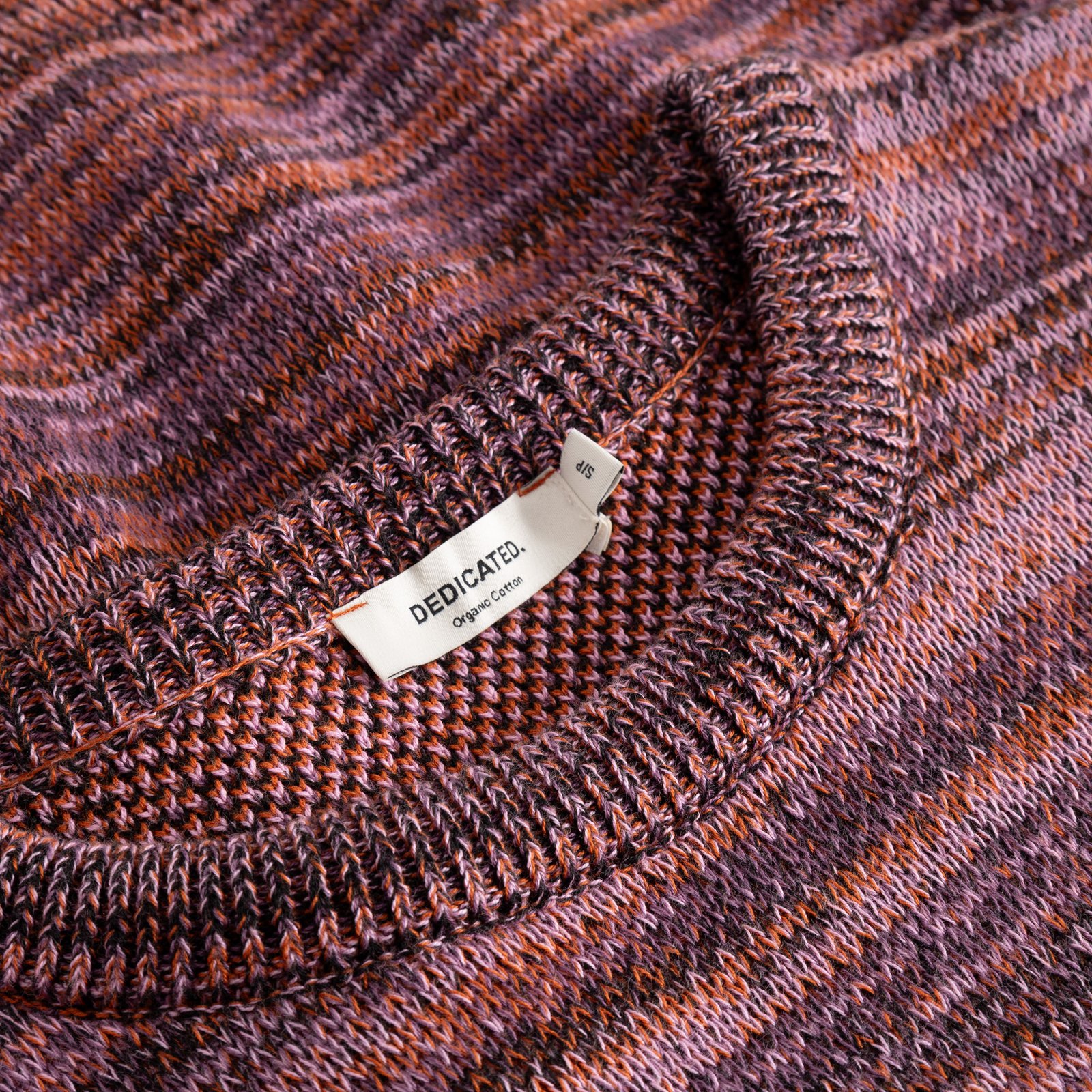 Close-up of the Arendal TY Swan sweater, showing the ribbed neckline and vibrant, multi-colored organic cotton jacquard knit.