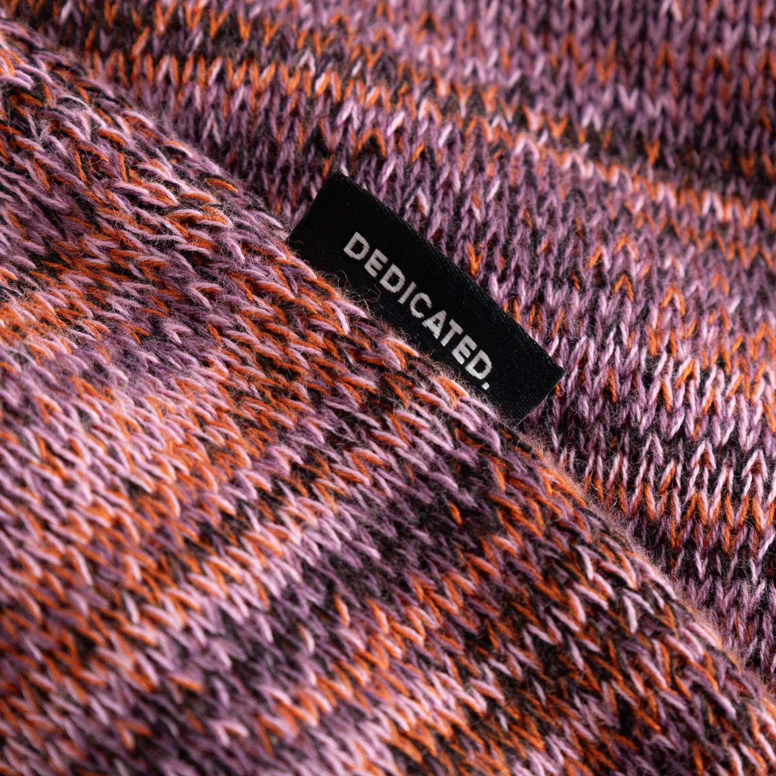 Close-up detail of the multi-colored knit fabric on the Sweater Arendal TY Swan, with the black Dedicated brand tab visible.