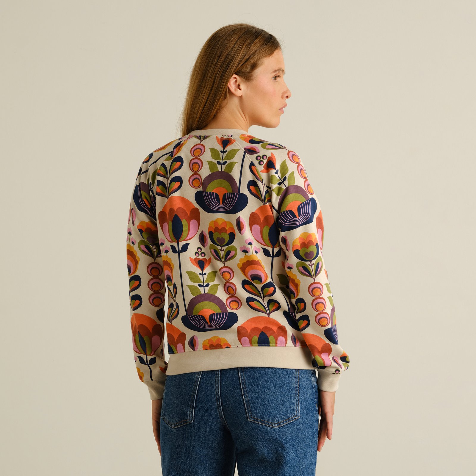 A stylish back view of a woman in the Ystad sweatshirt, featuring the bold and colorful Autumn Harvest floral pattern.