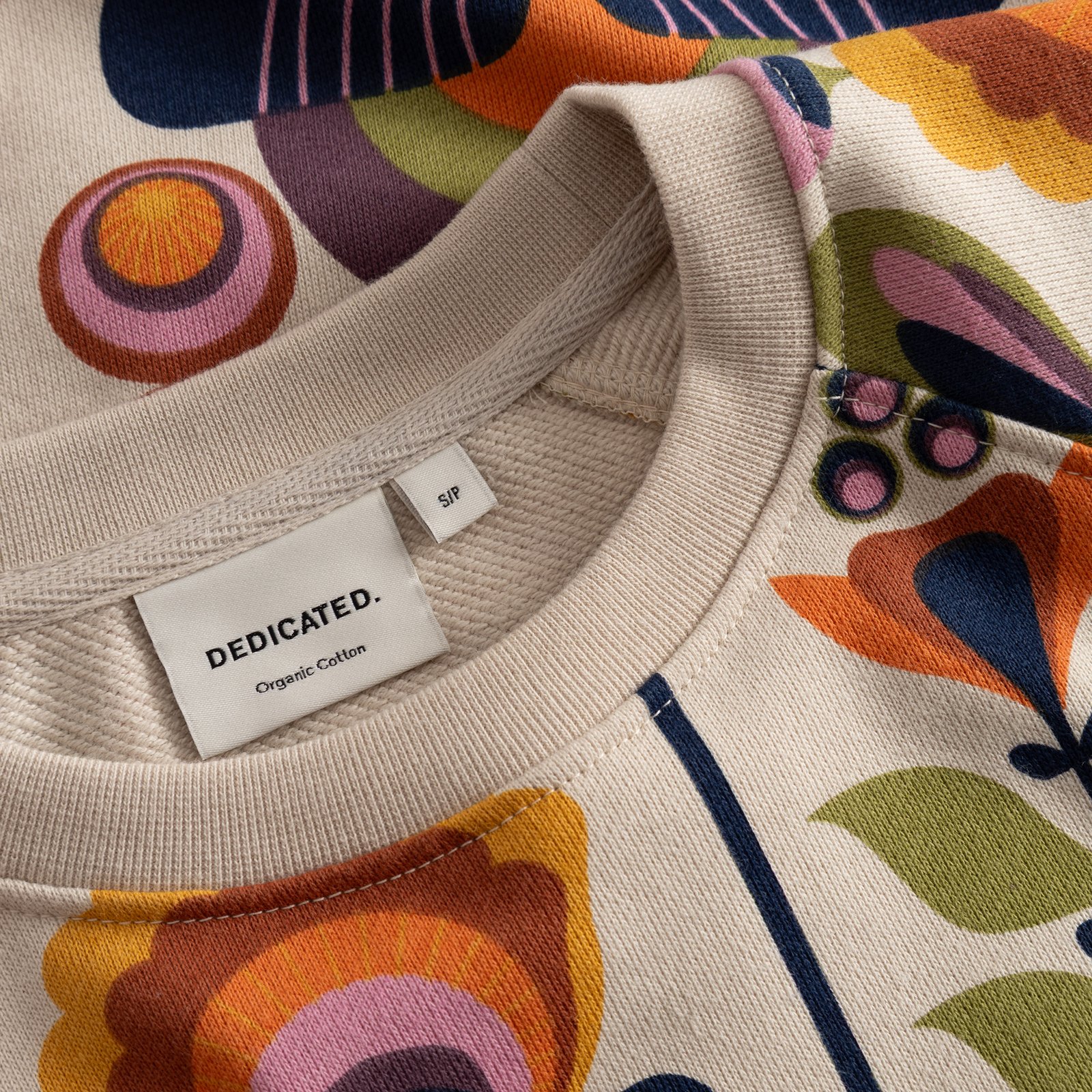 Close-up of the Ystad sweatshirt's ribbed neckline, showing the fun, retro Autumn Harvest print and brand label.