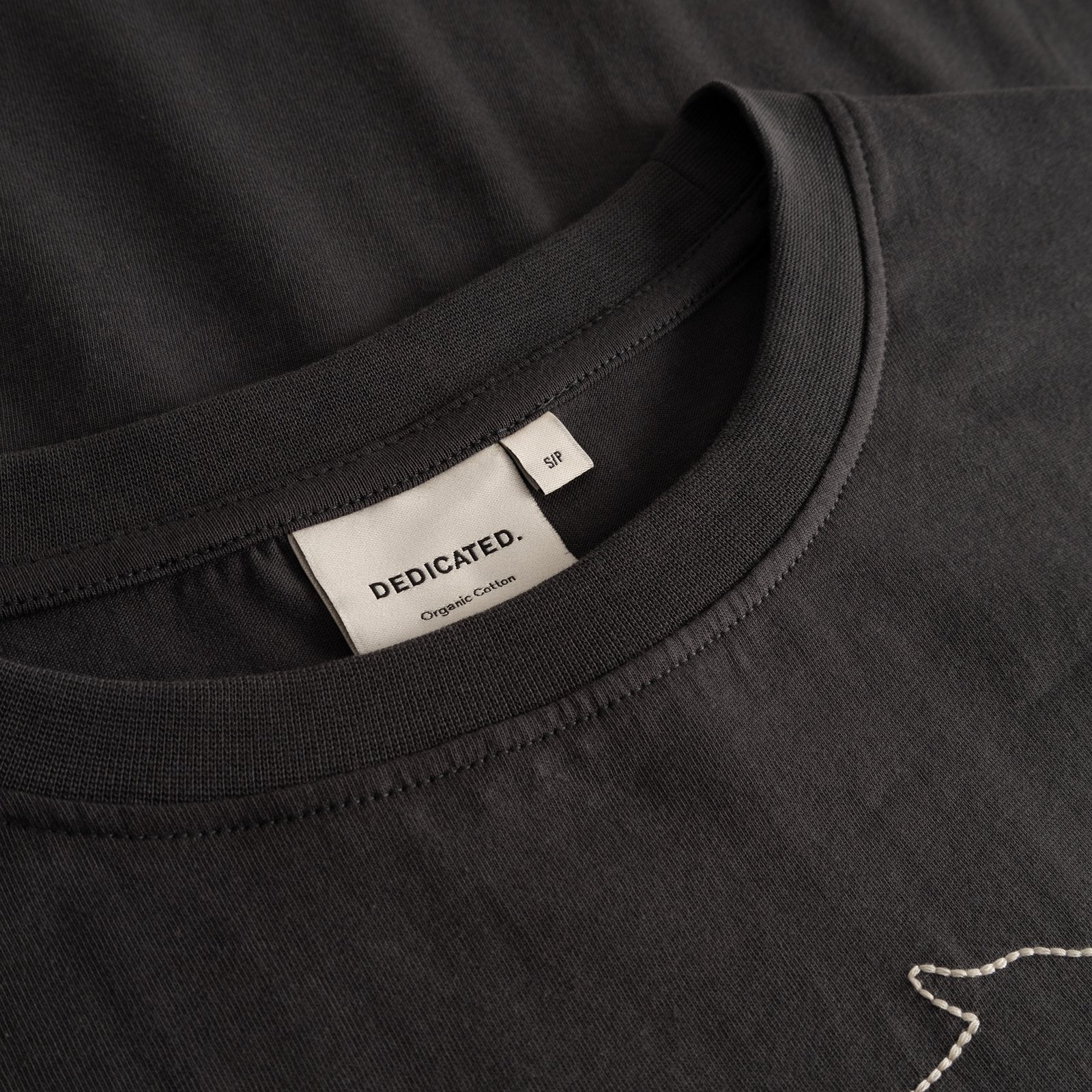 Detailed close-up of the charcoal T-shirt Vadstena's neckline, showing the Dedicated brand label and ribbed collar.
