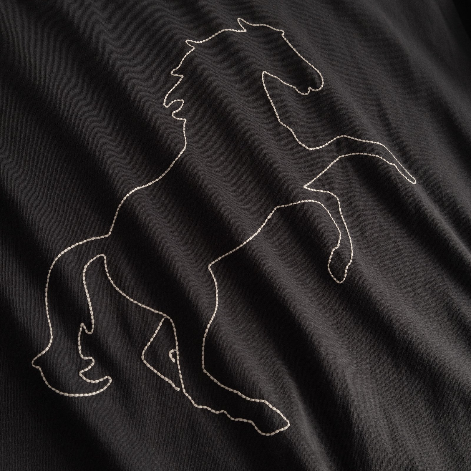 Close-up of the Wild Horse stitch embroidery on the charcoal Vadstena T-shirt.