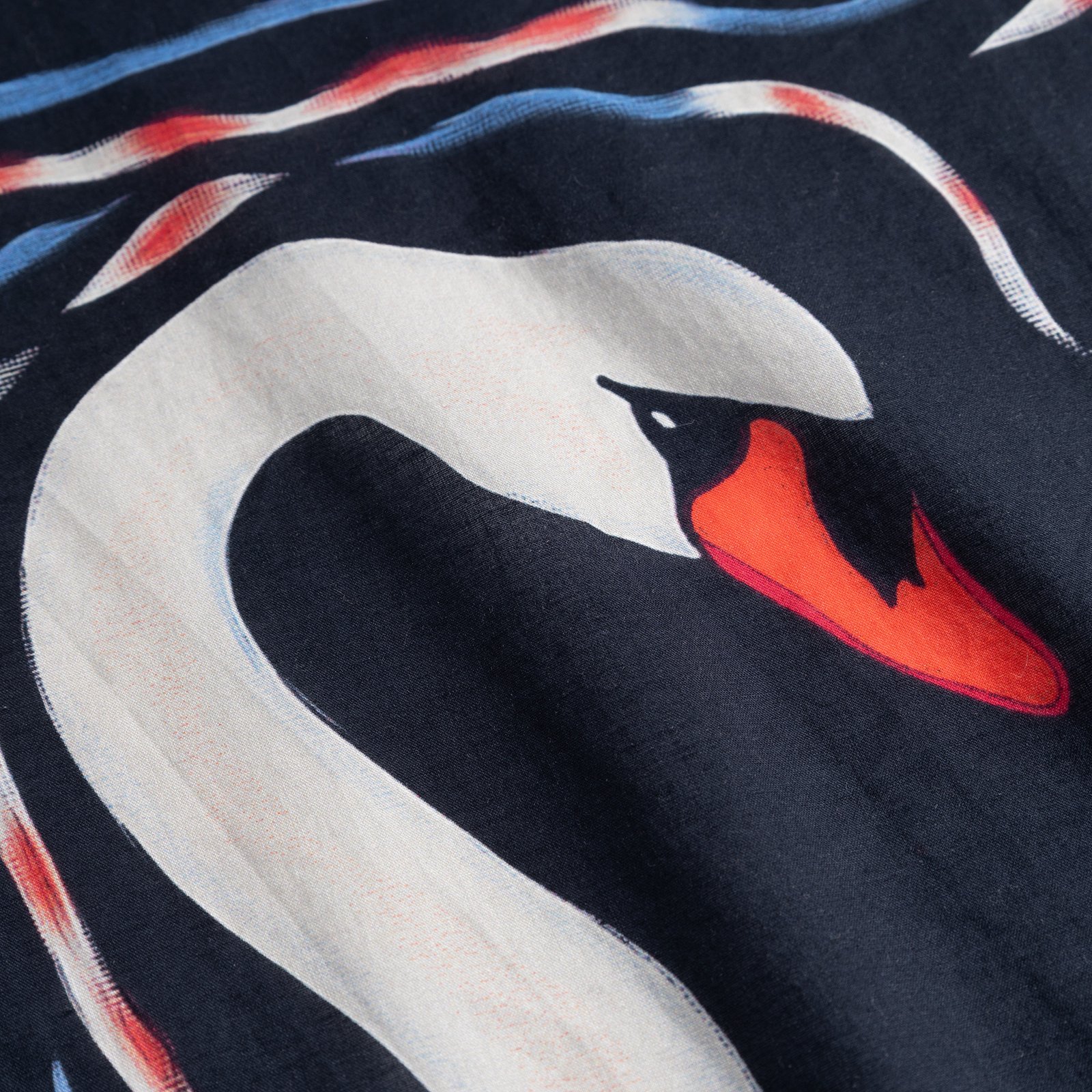 A close-up detail shot of the Scarf Kullavik, showcasing the beautiful painted swan print on a dark blue background.