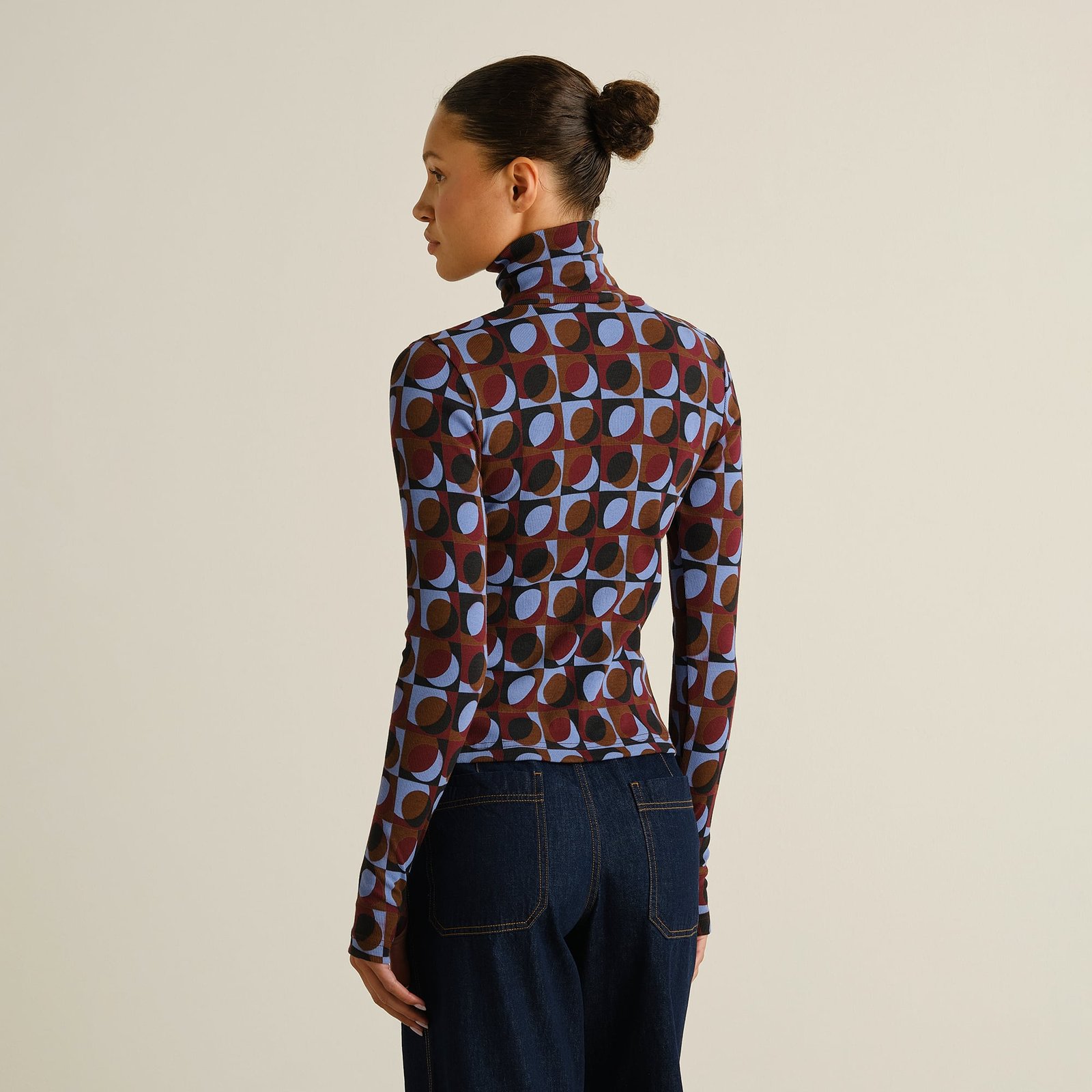 A woman with her hair in a bun models the Rib Top Malma in Retro Geo print from the back, showing its slim fit with jeans.