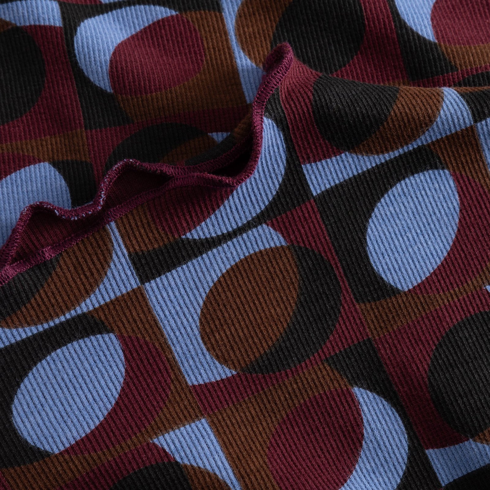 Close-up detail of the Rib Dress Lofta showing the ribbed fabric with a Retro Geo print and a delicate lettuce seam edge.