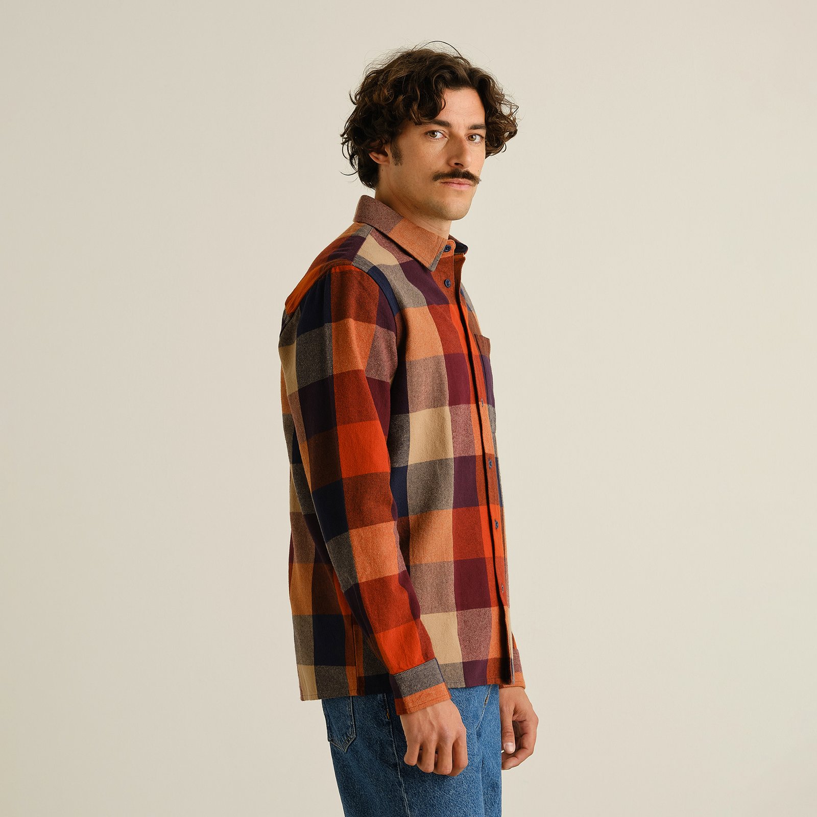 Model looks back, showing off the relaxed fit of the Rute Flannel Shirt in a warm, muted multi-color check pattern.