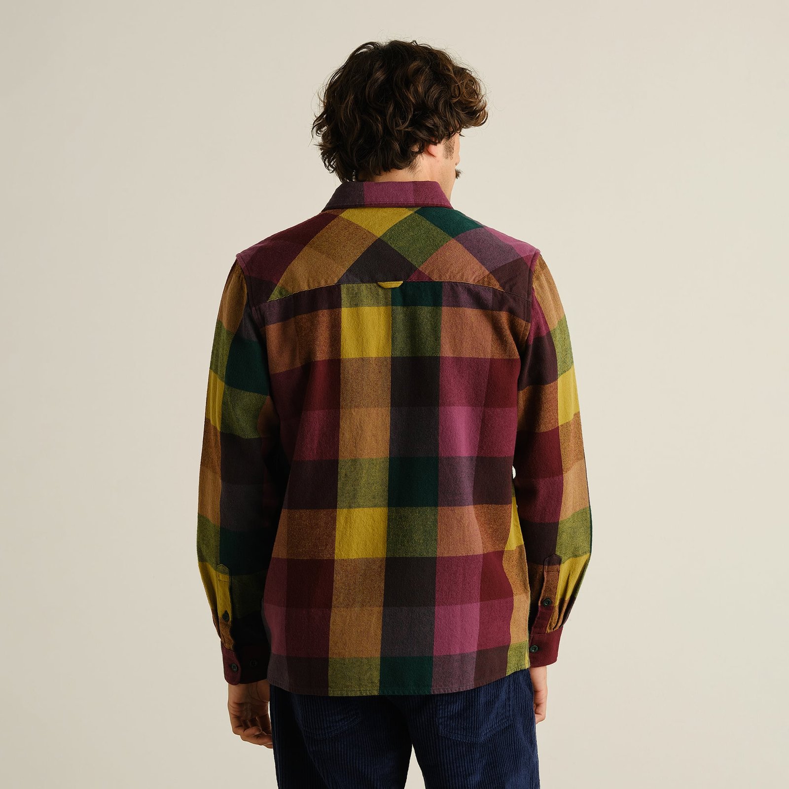Back view of a man wearing the Dedicated Rute Flannel Shirt in a bold and colorful oversized check pattern.