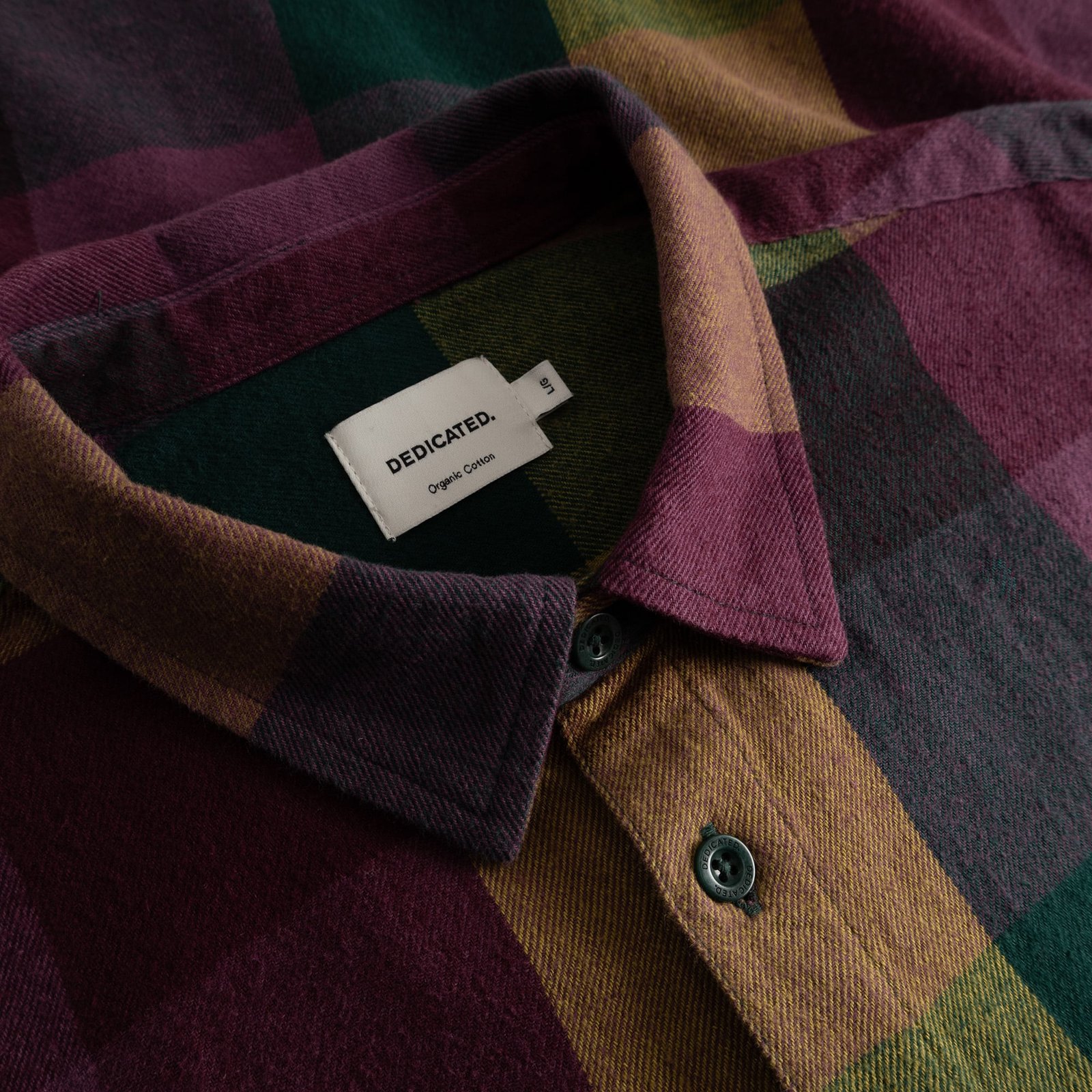 Close-up of the collar on the Rute Flannel Shirt, showcasing its soft texture and bold check in plum, mustard, and green.