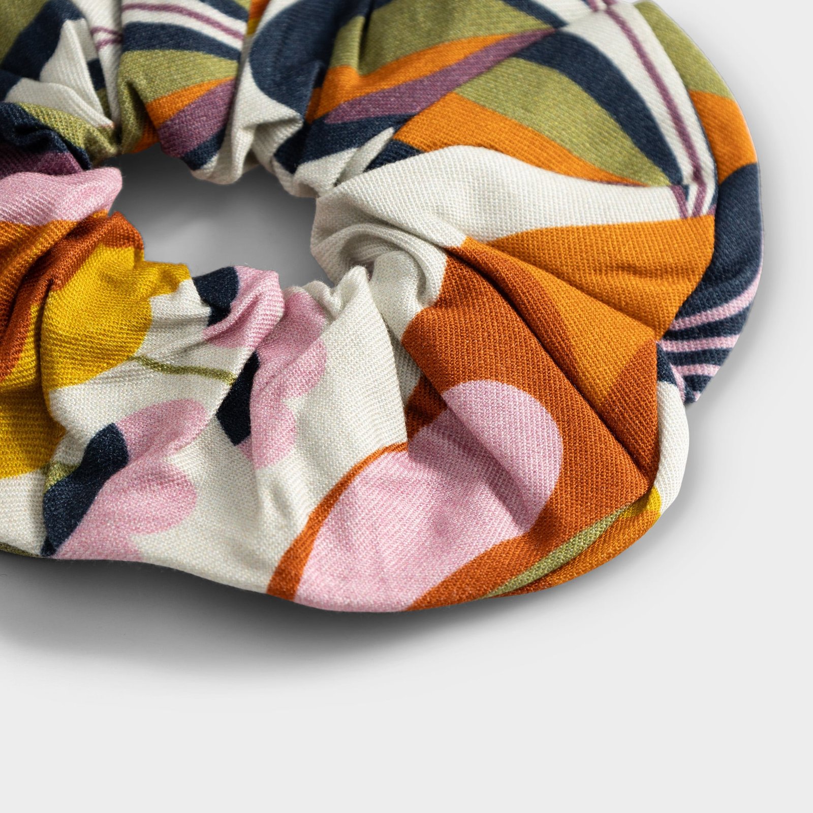 A close-up shot showcasing the soft texture and vibrant abstract pattern of the Autumn Harvest multi-color scrunchie.