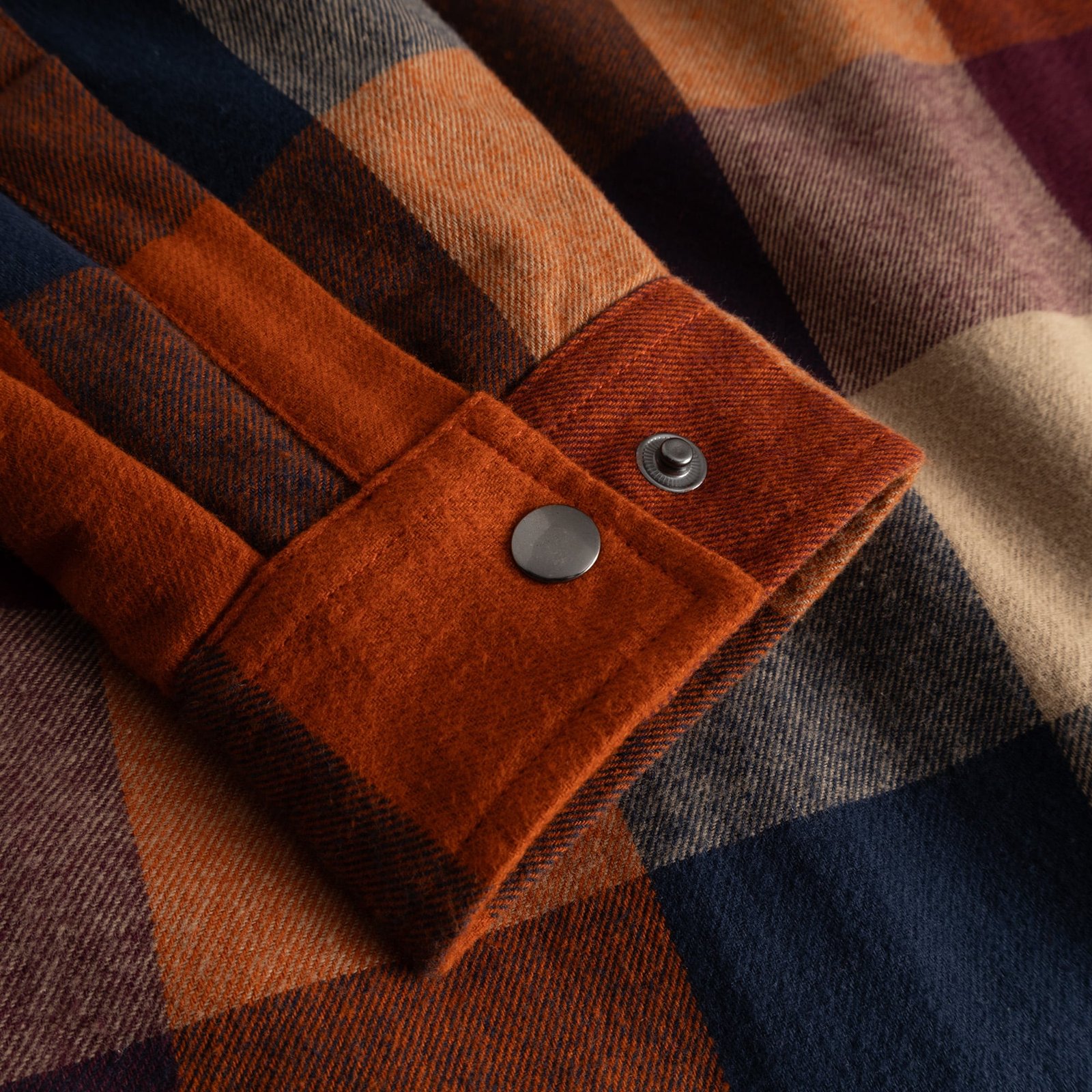 Close-up detail of the cuff on the Torp jacket, featuring a muted multi-color flannel check and sturdy metal press buttons.