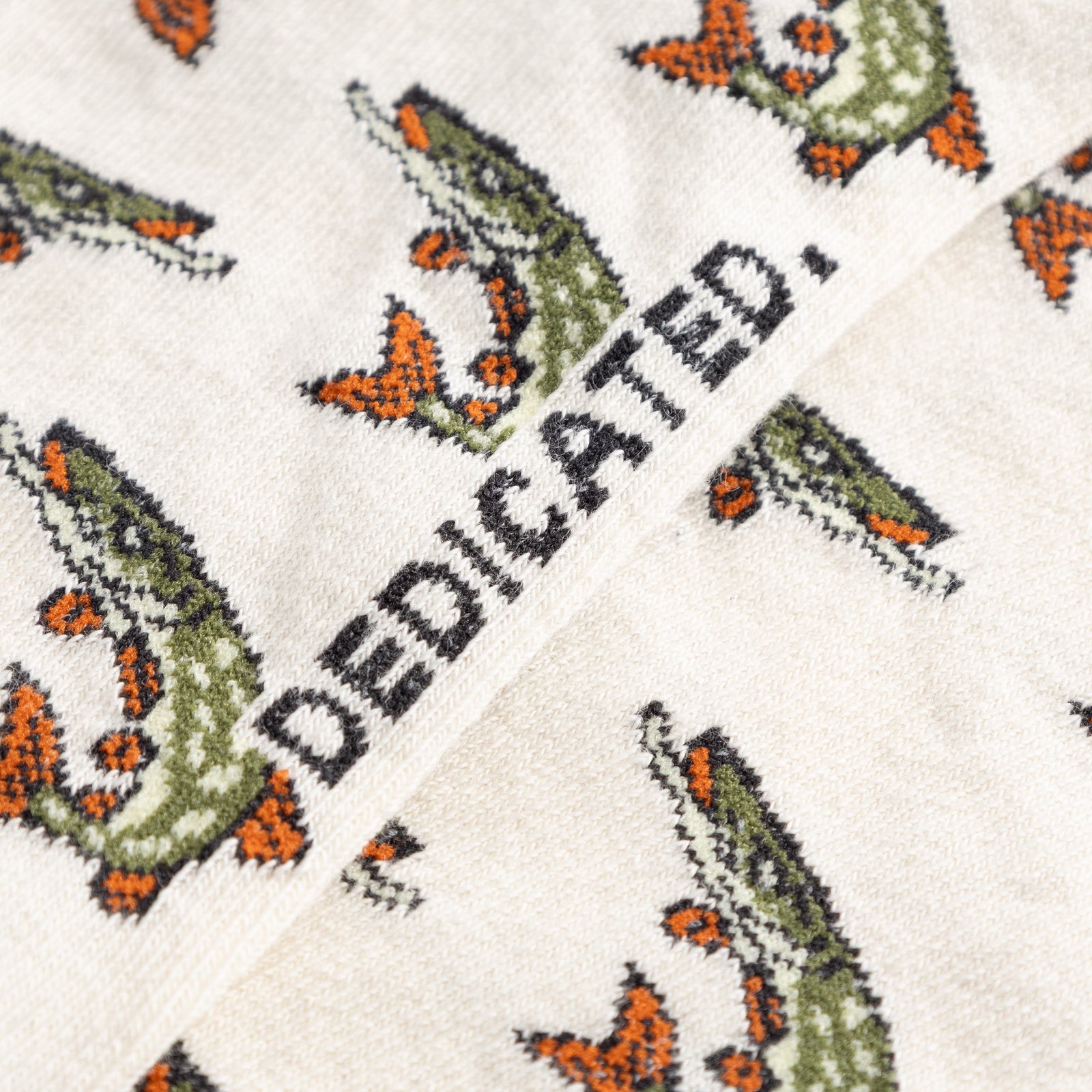 A detailed shot of the off-white Sigtuna Pikes socks, showcasing the intricate fish pattern and the classic Dedicated logo.