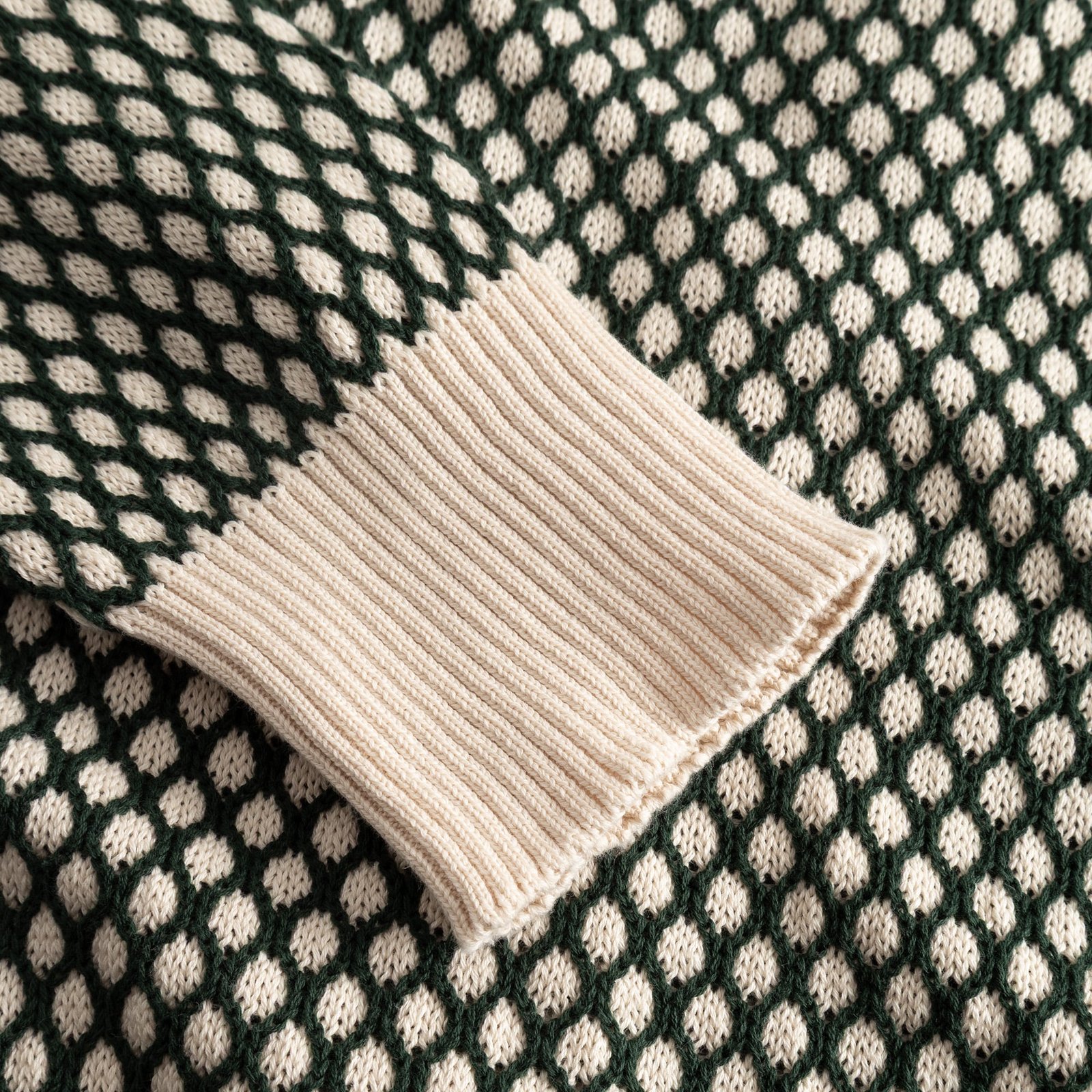 Närbild på ärmen på Kanan Cardigan, som visar den texturerade bubbelstickningen i mörkgrönt och vaniljvitt.