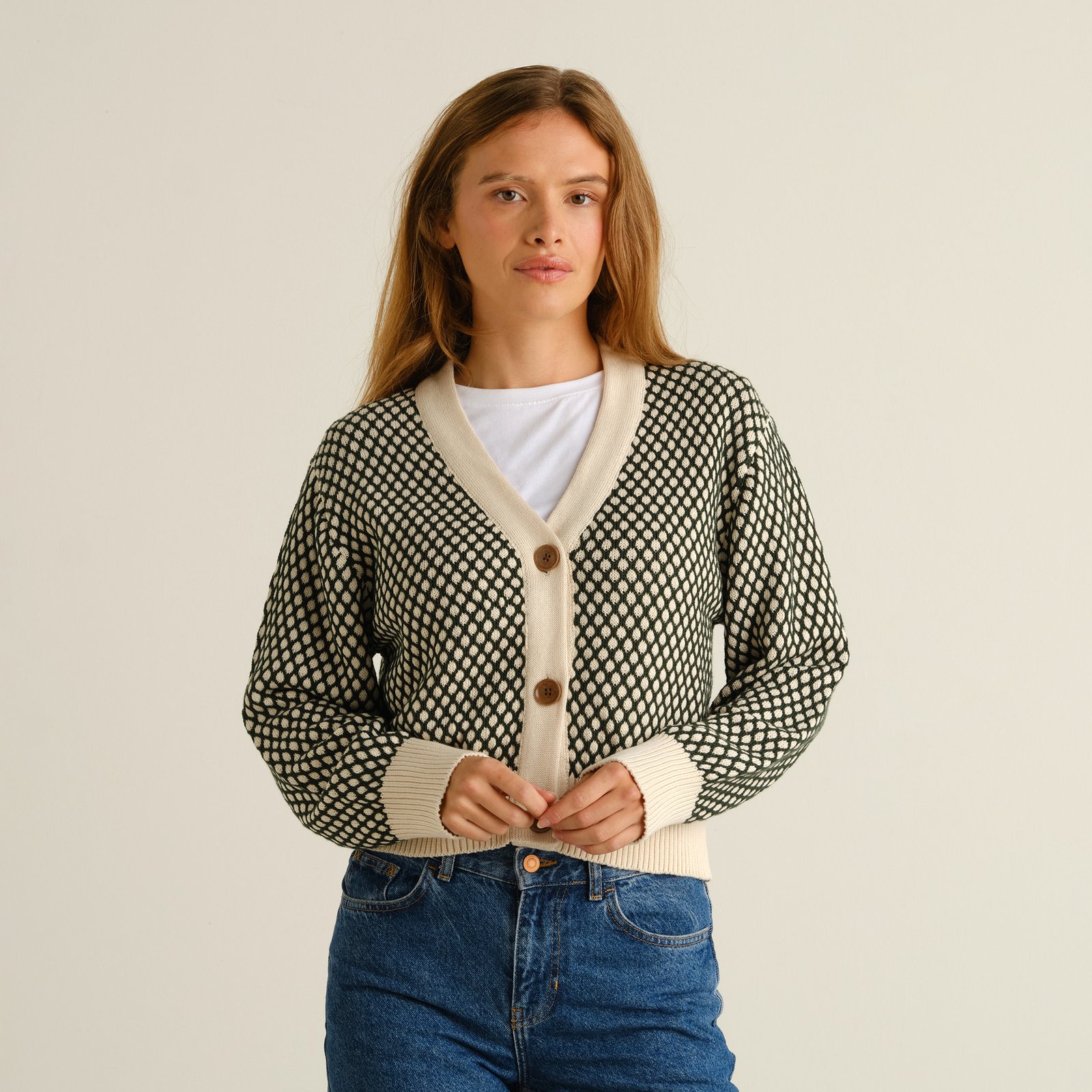Modell som bär den mörkgröna och vaniljvitt mönstrade koftan Kanan Bubble Knit tillsammans med jeans.