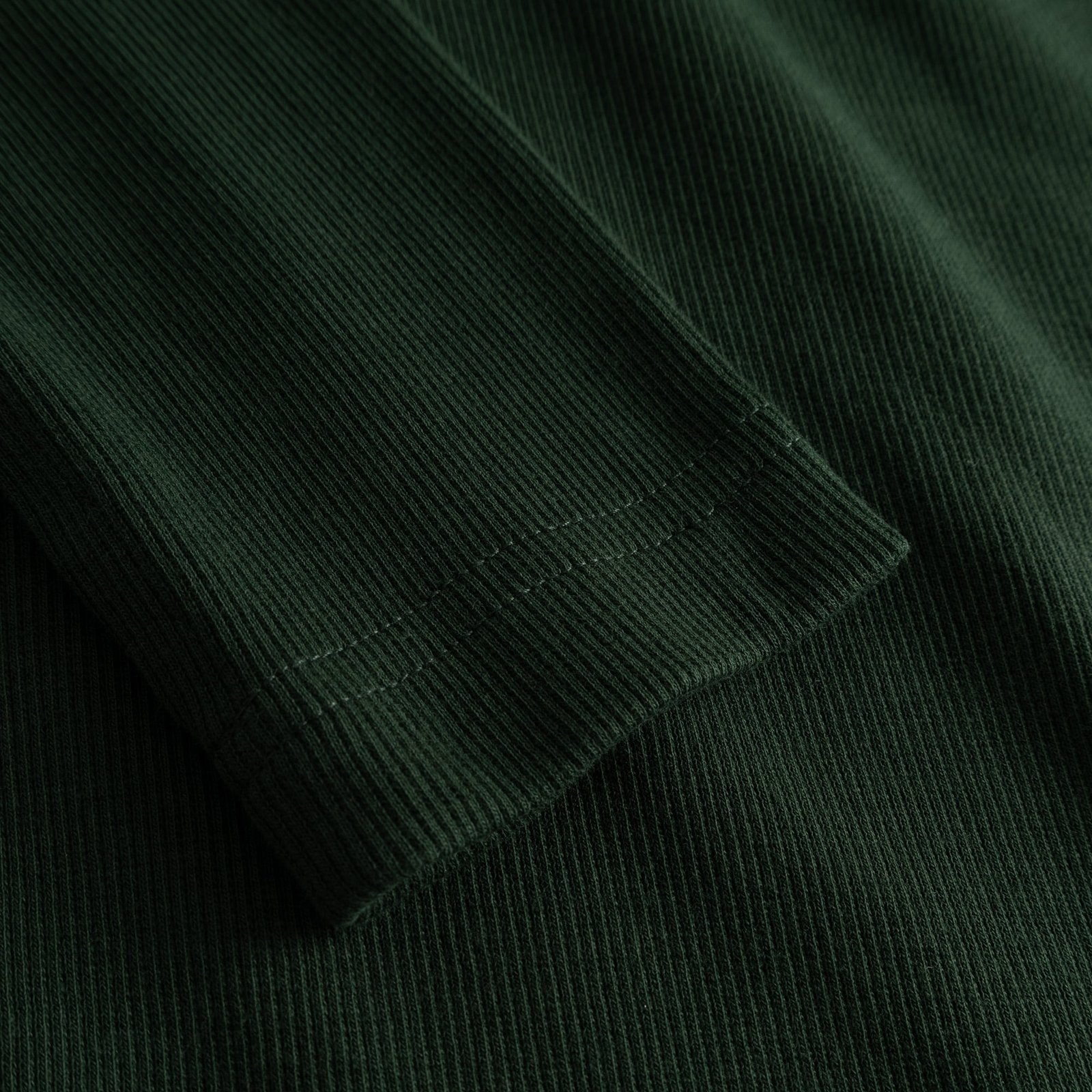 A detailed close-up of the sleeve on the Rib Top Malma, showcasing the fine ribbed texture in a deep dark green.