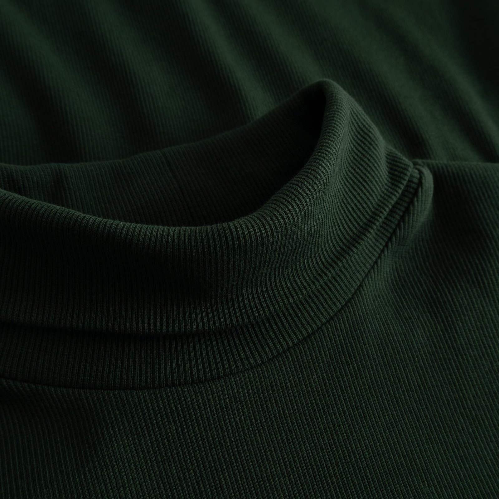A detailed close-up of the Rib Top Malma in dark green, showing the soft ribbed texture and cozy turtleneck collar.