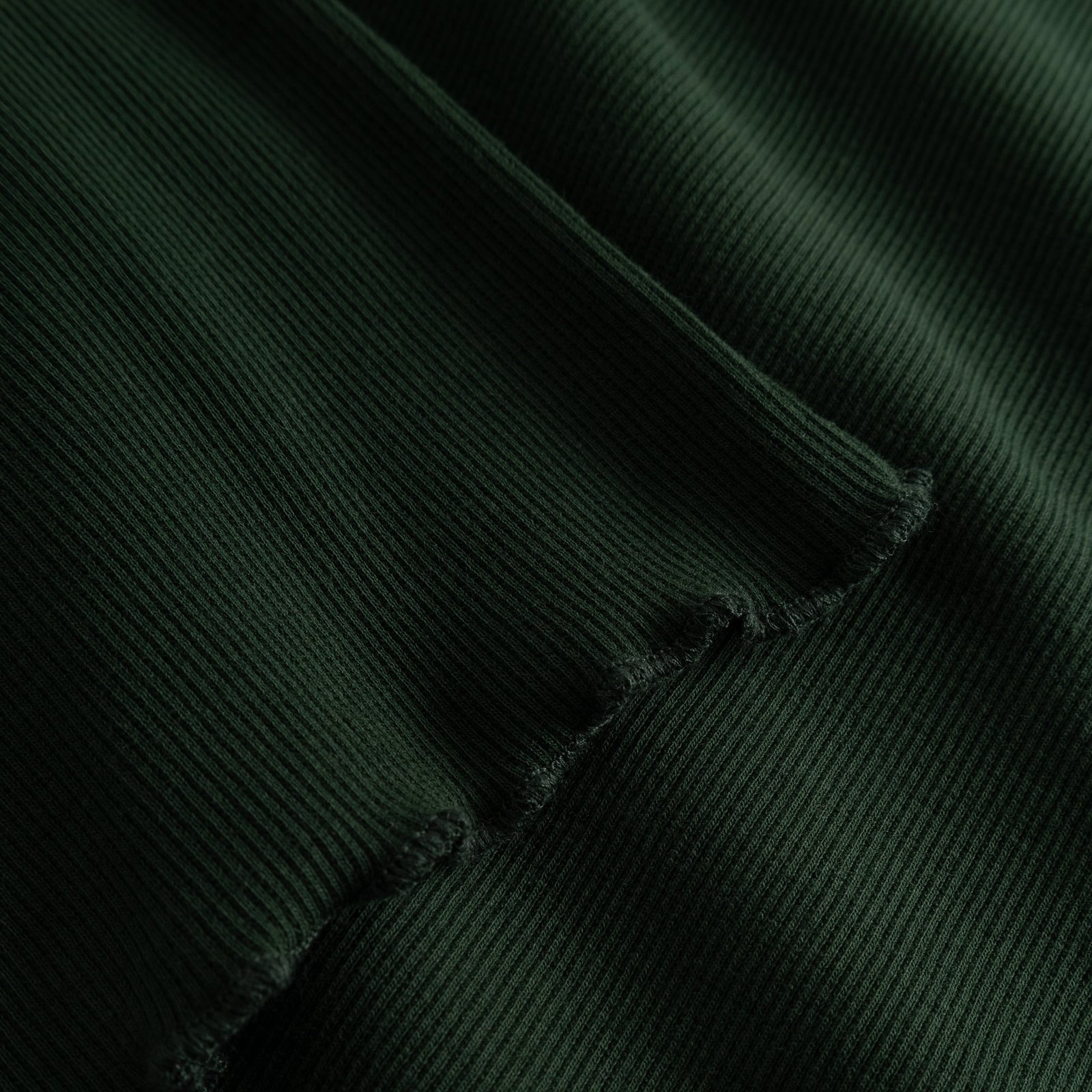 A close-up of the Rib Top Ryd in Dark Green, showing the soft ribbed texture and delicate wavy finish of the lettuce seam.