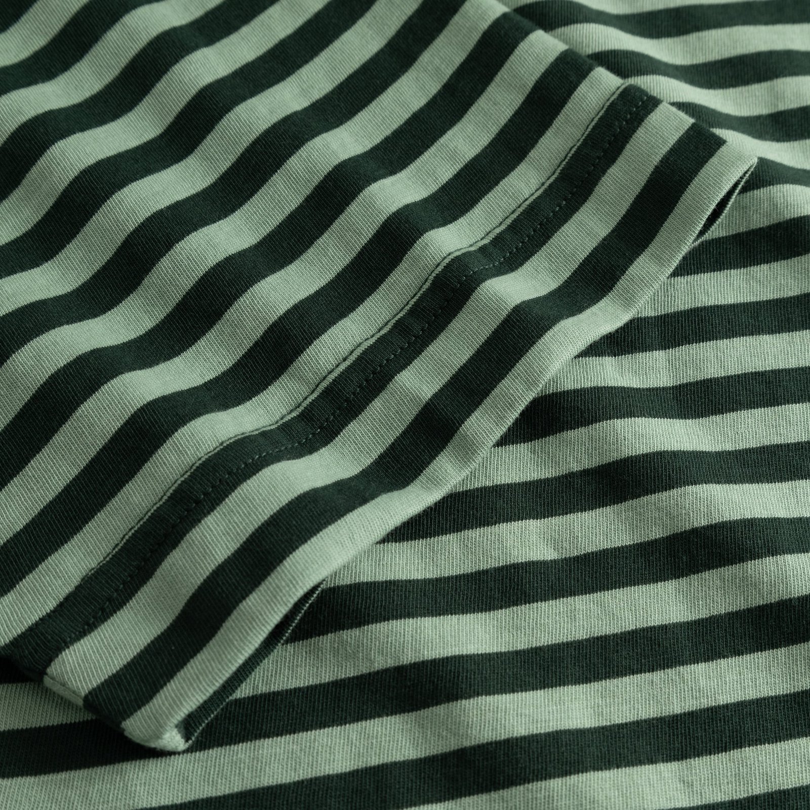 Close-up shot of the striped fabric and sleeve detail on the T-shirt Vadstena in dark and granite green.