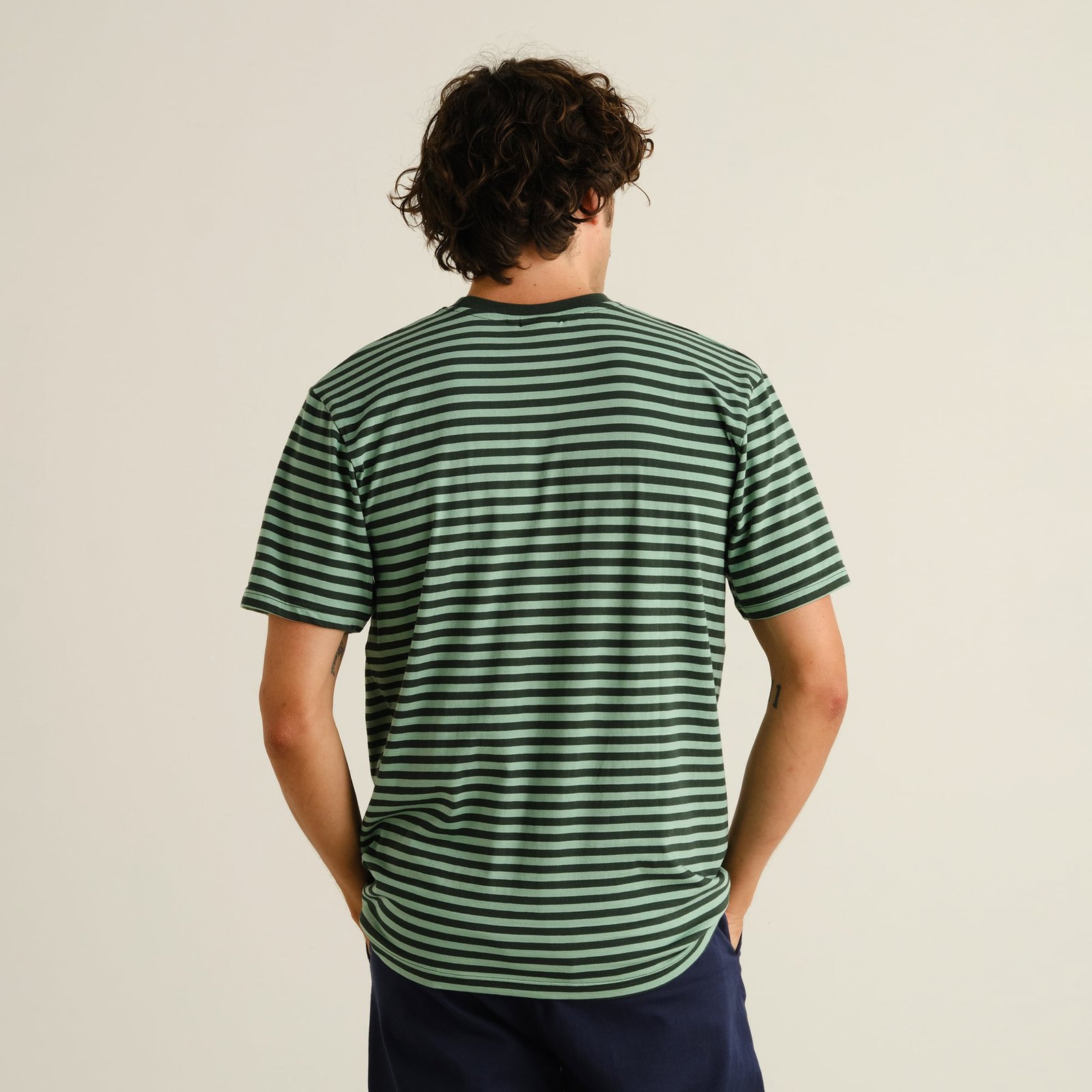 Man seen from behind wearing the T-shirt Stockholm Stripes in Dark Green and Granite Green.