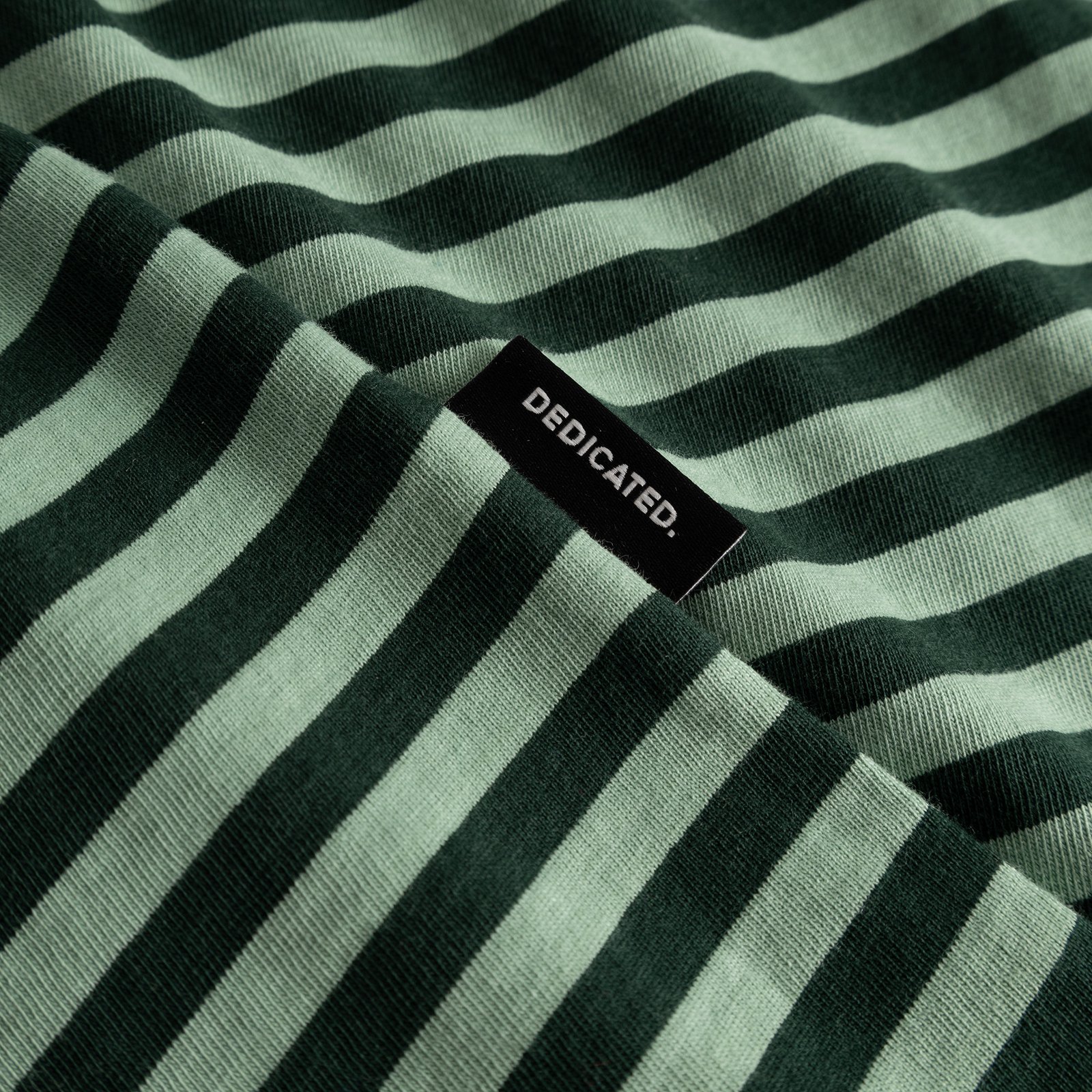 Close-up of the T-shirt Stockholm Stripes in dark and granite green, showing the fabric texture and black Dedicated label.