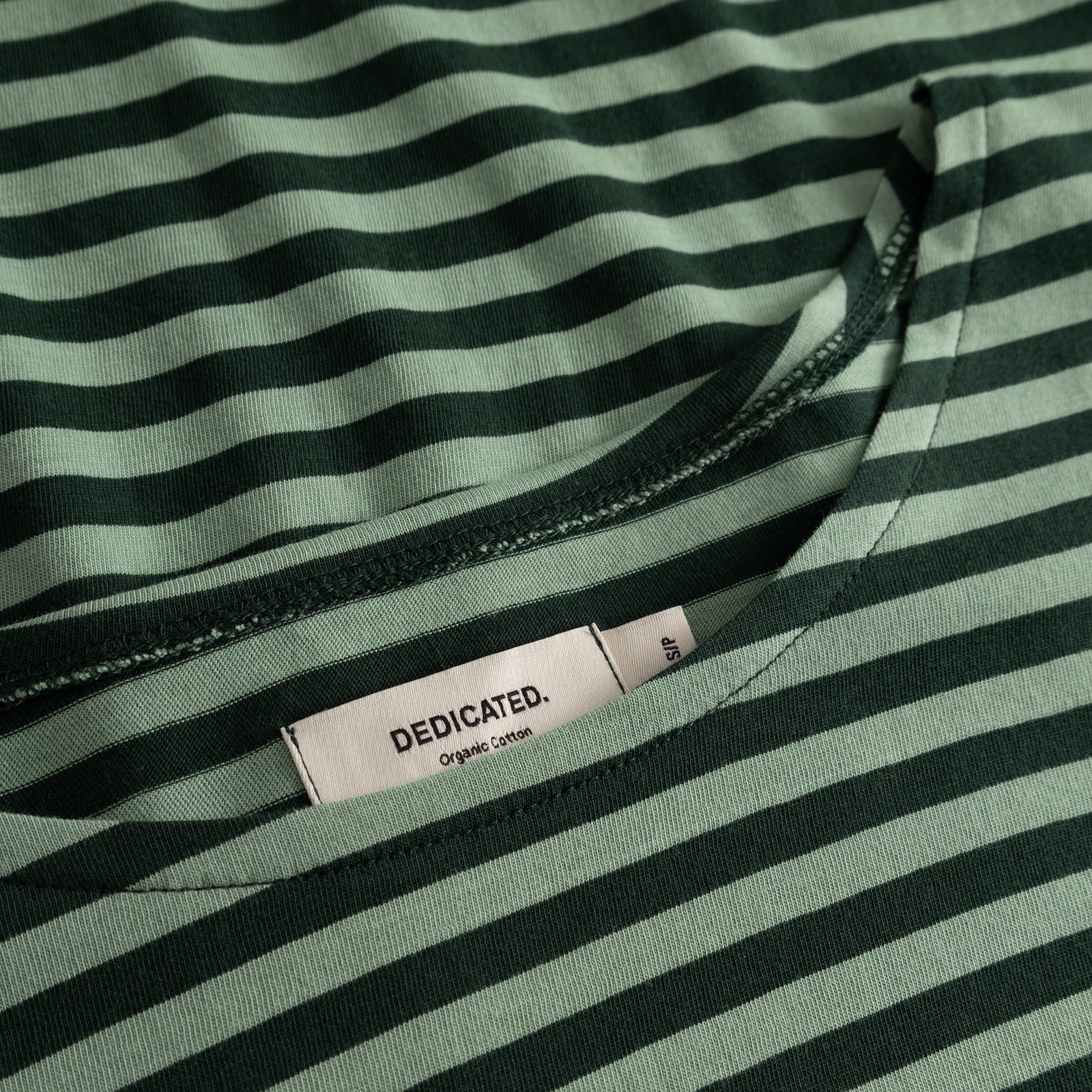 Close-up of the Humledal top, highlighting the dark and granite green striped organic cotton and the Dedicated label.