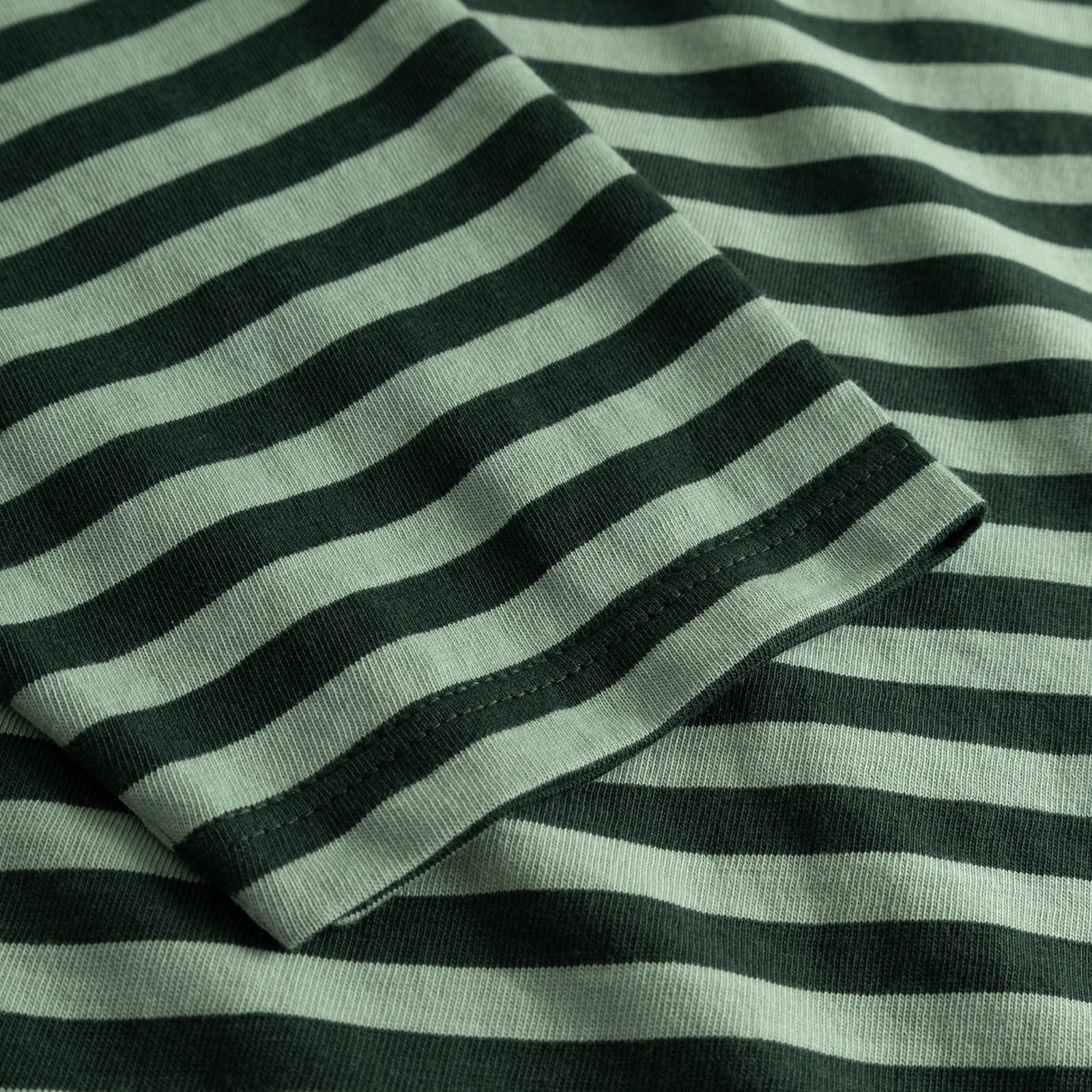 A detailed close-up of the sleeve on the Top Humledal, showing the dark green and granite green striped organic cotton.