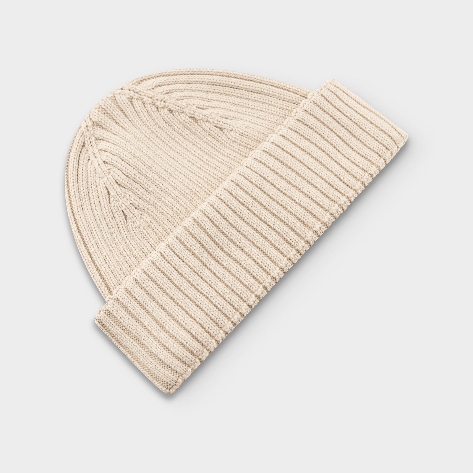Overhead view of the Beanie Rutvik in Oat White. The organic cotton hat features a classic rib-knit texture and folded hem.