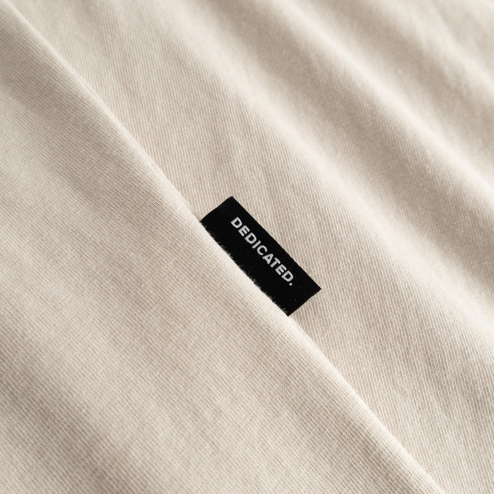 A close-up look at our T-shirt Stockholm in Oat White, featuring the subtle and classic Dedicated side label.