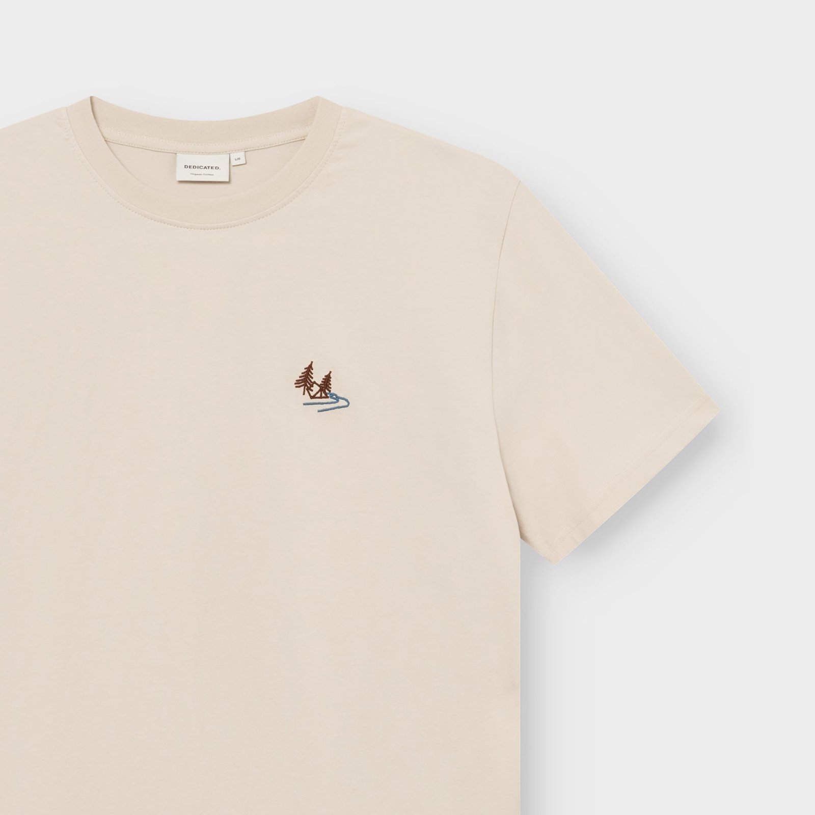 Close-up of the oat white T-shirt Stockholm Camp Creek, showing the detailed nature embroidery on the chest and brand label.