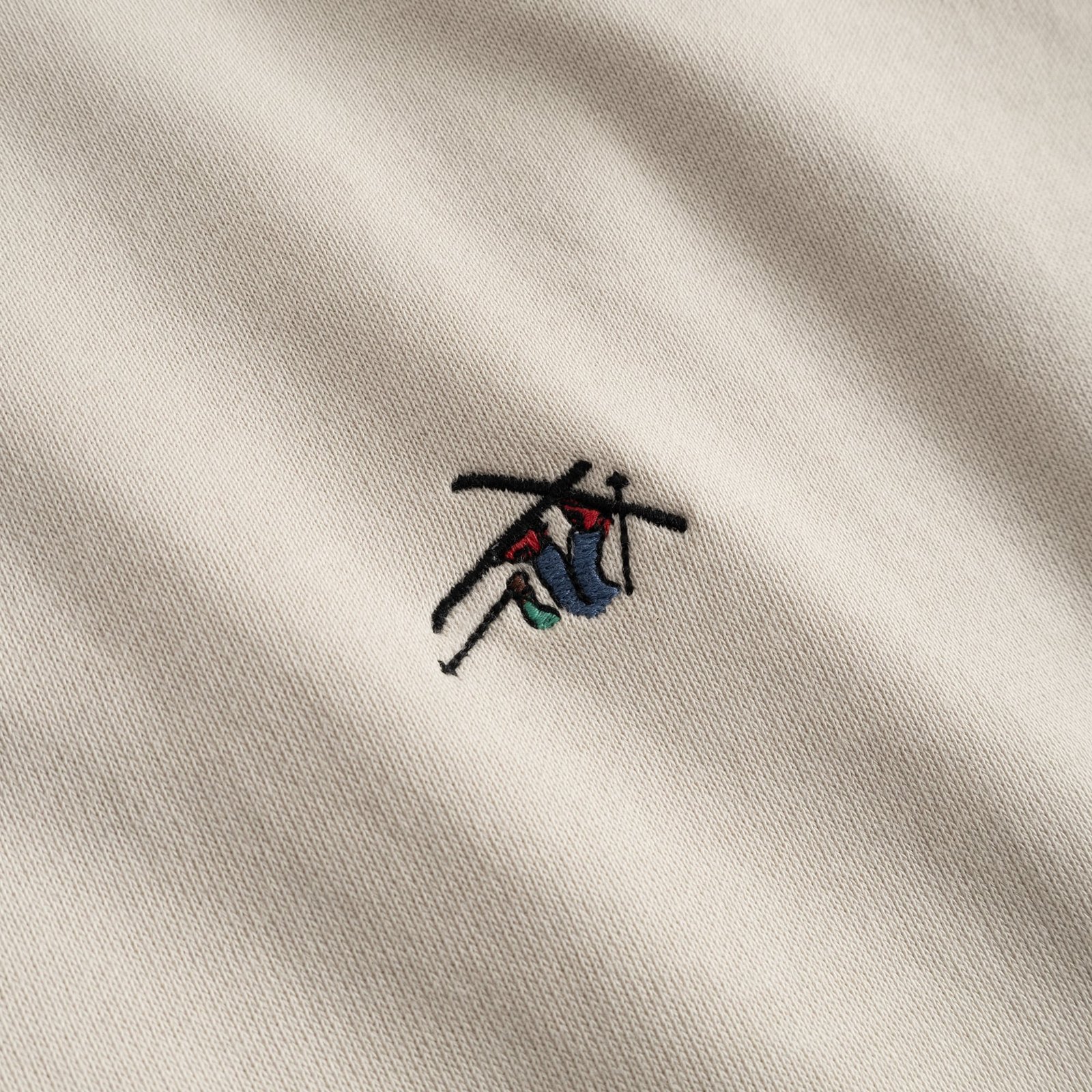 Close-up of the playful 'Ski Crash' embroidery on the chest of the Dedicated Sweatshirt Malmoe in oat white.