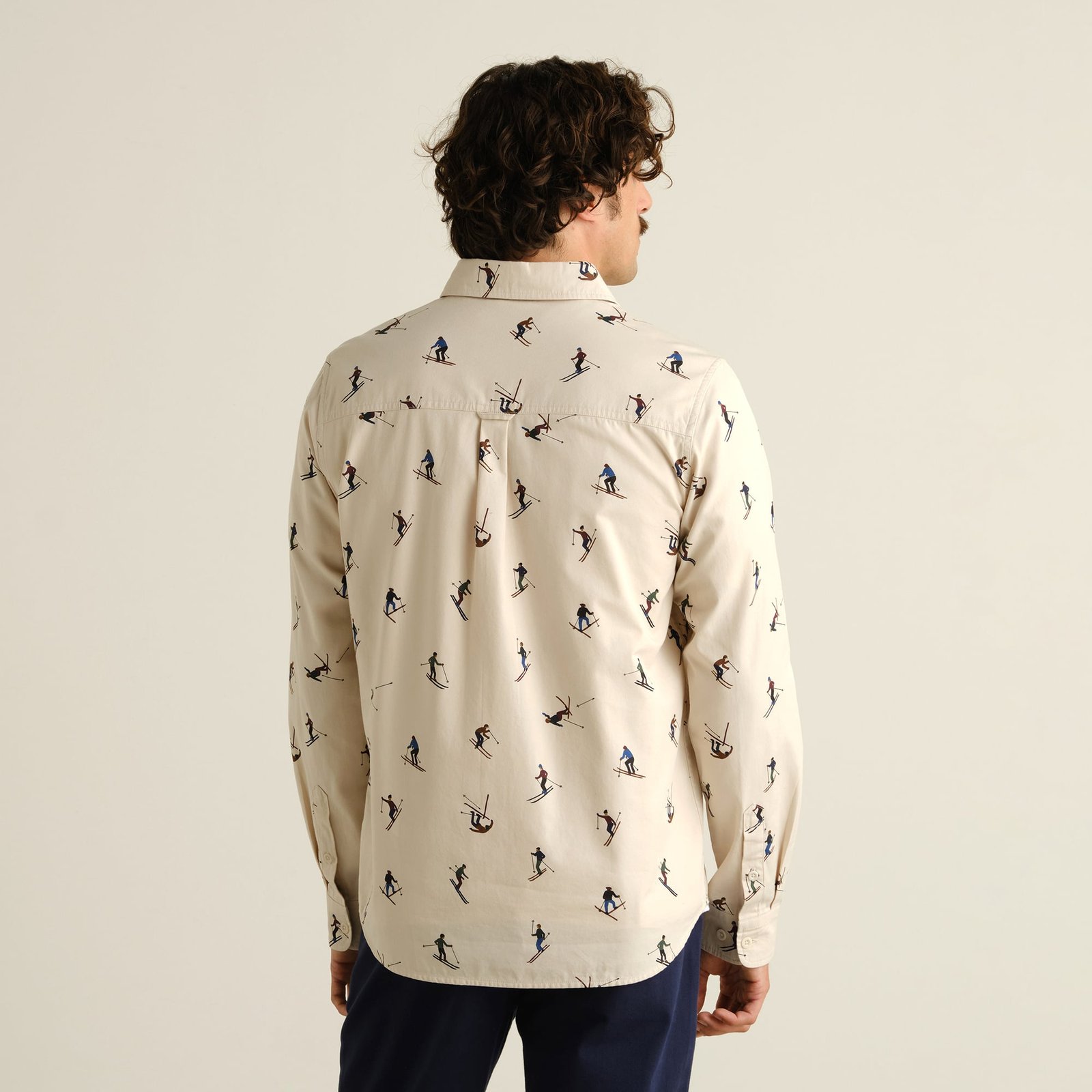 Back view of a model wearing the Shirt Lunnevik Ski Team Oat White, showing the playful all-over skier print.